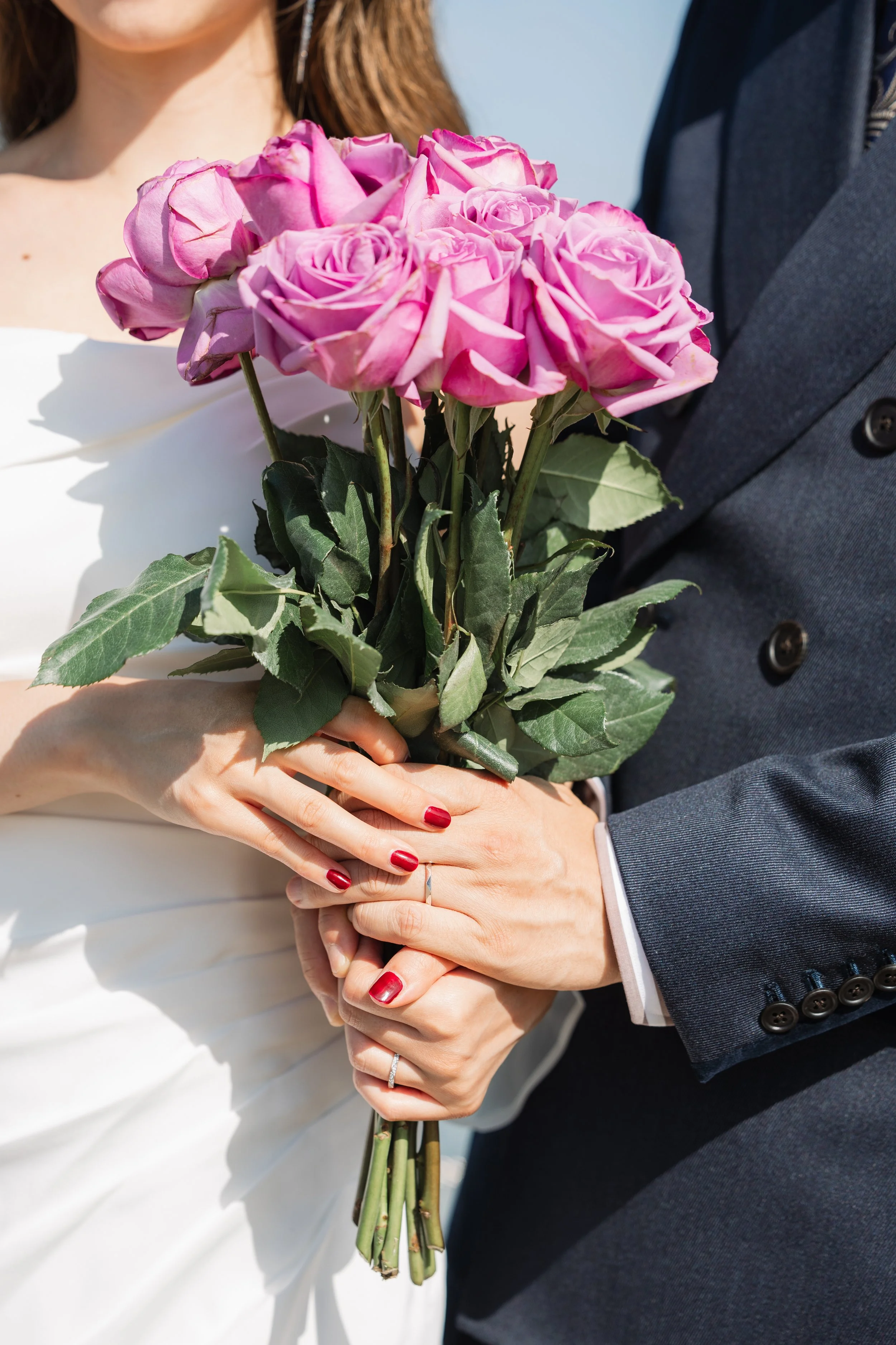結婚式の新郎新婦がピンクのバラの花束を持っている写真
