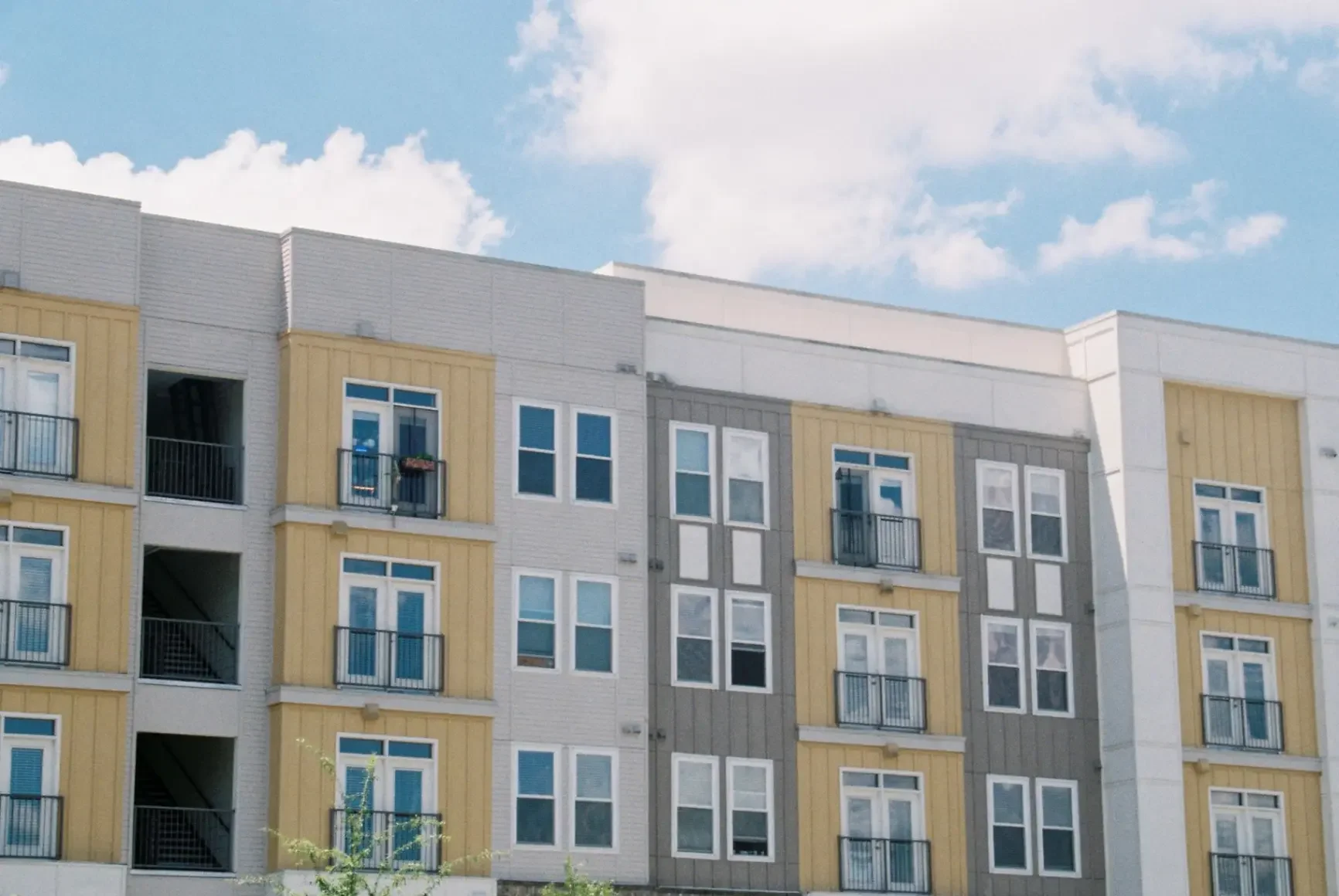 Contemporary apartment building exterior with yellow and grey panels under a clear blue sky