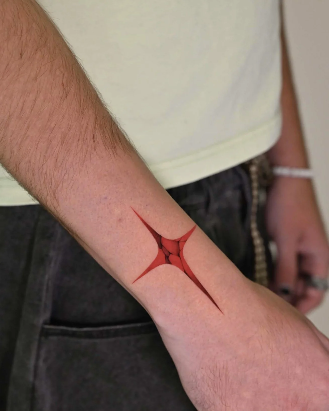 Red and black cracked abstract arm tattoo by Megink.