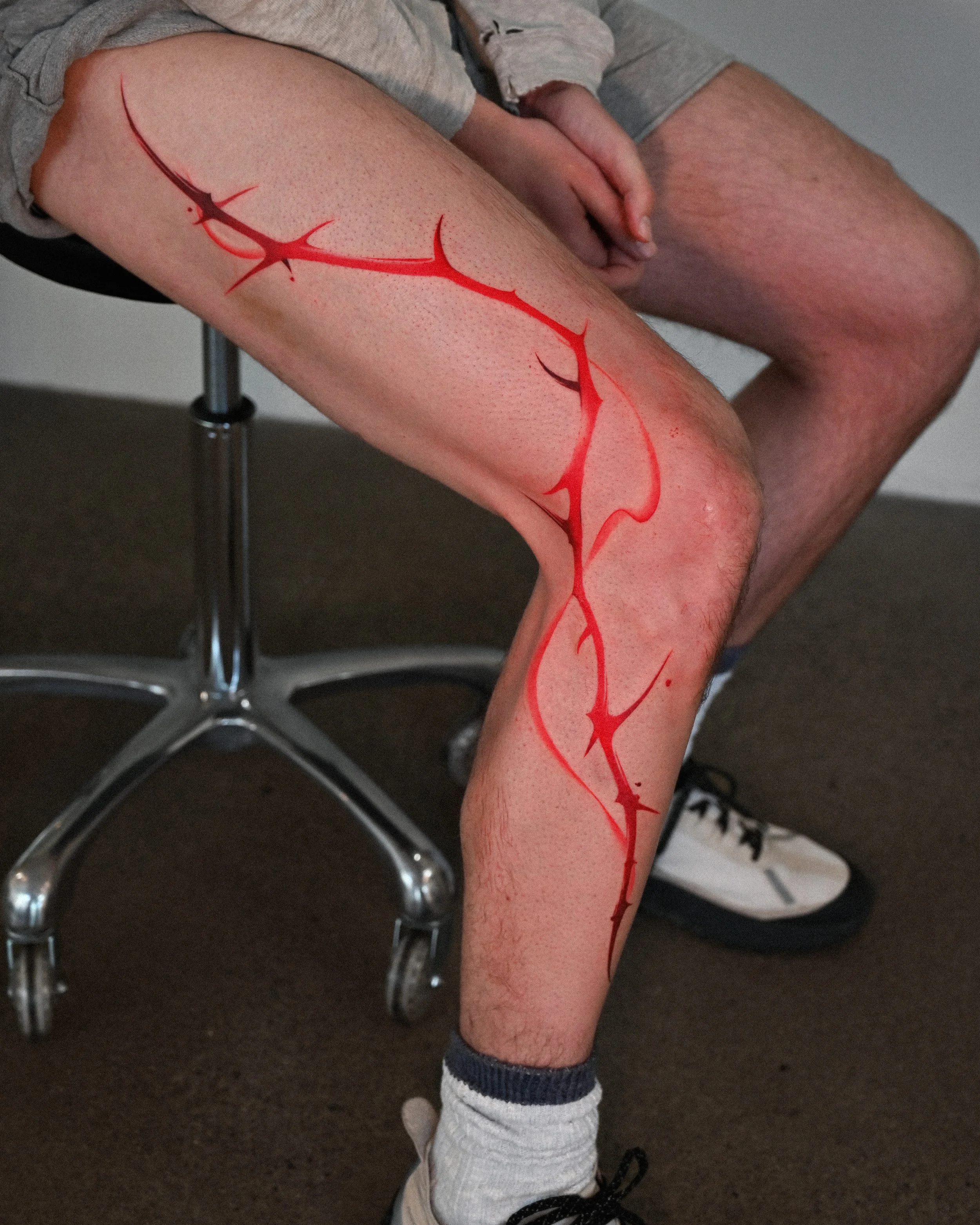Large red abstract thorn leg tattoo by Megink.