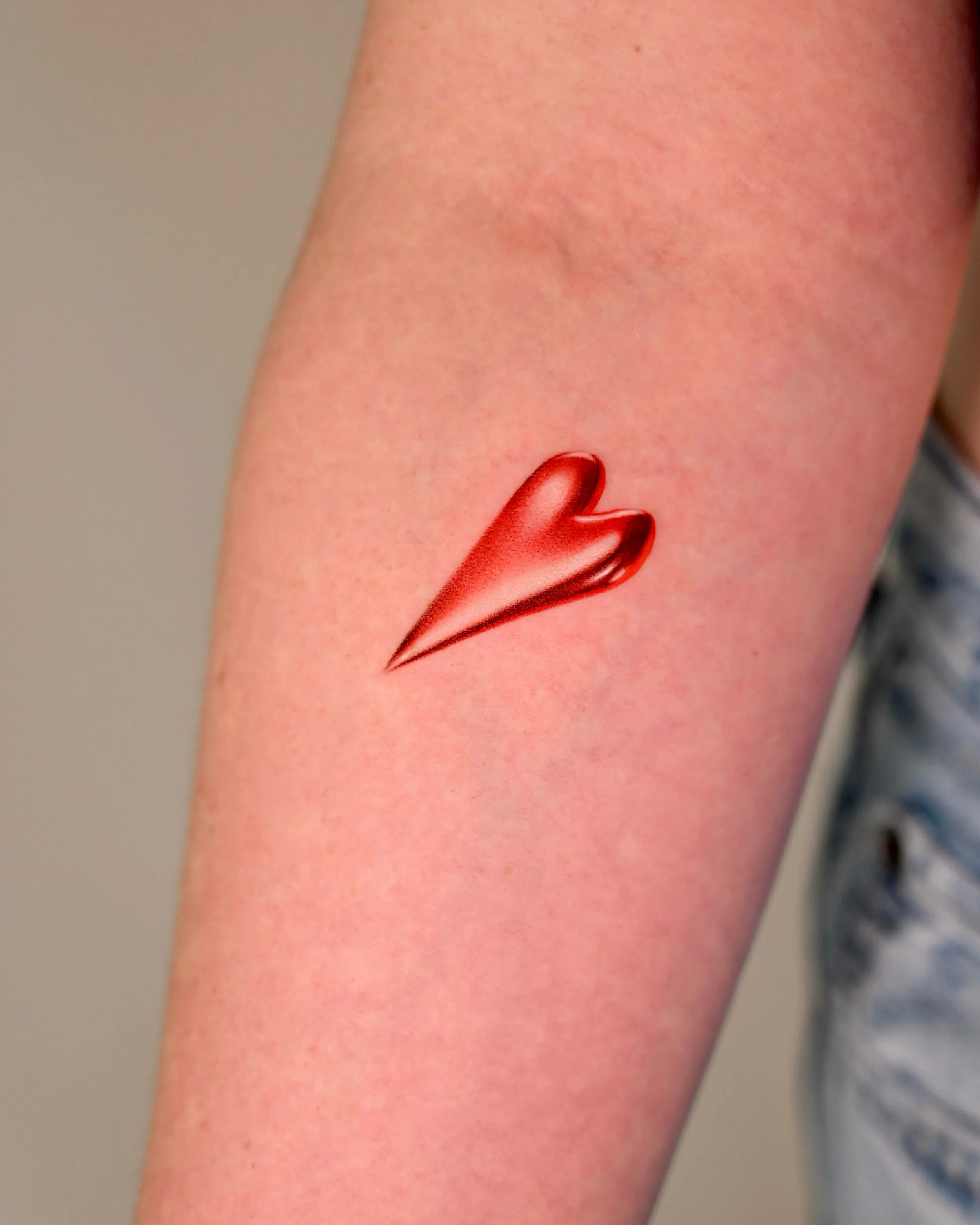 Small red heart tattoo by Seattle tattoo artist Megink.