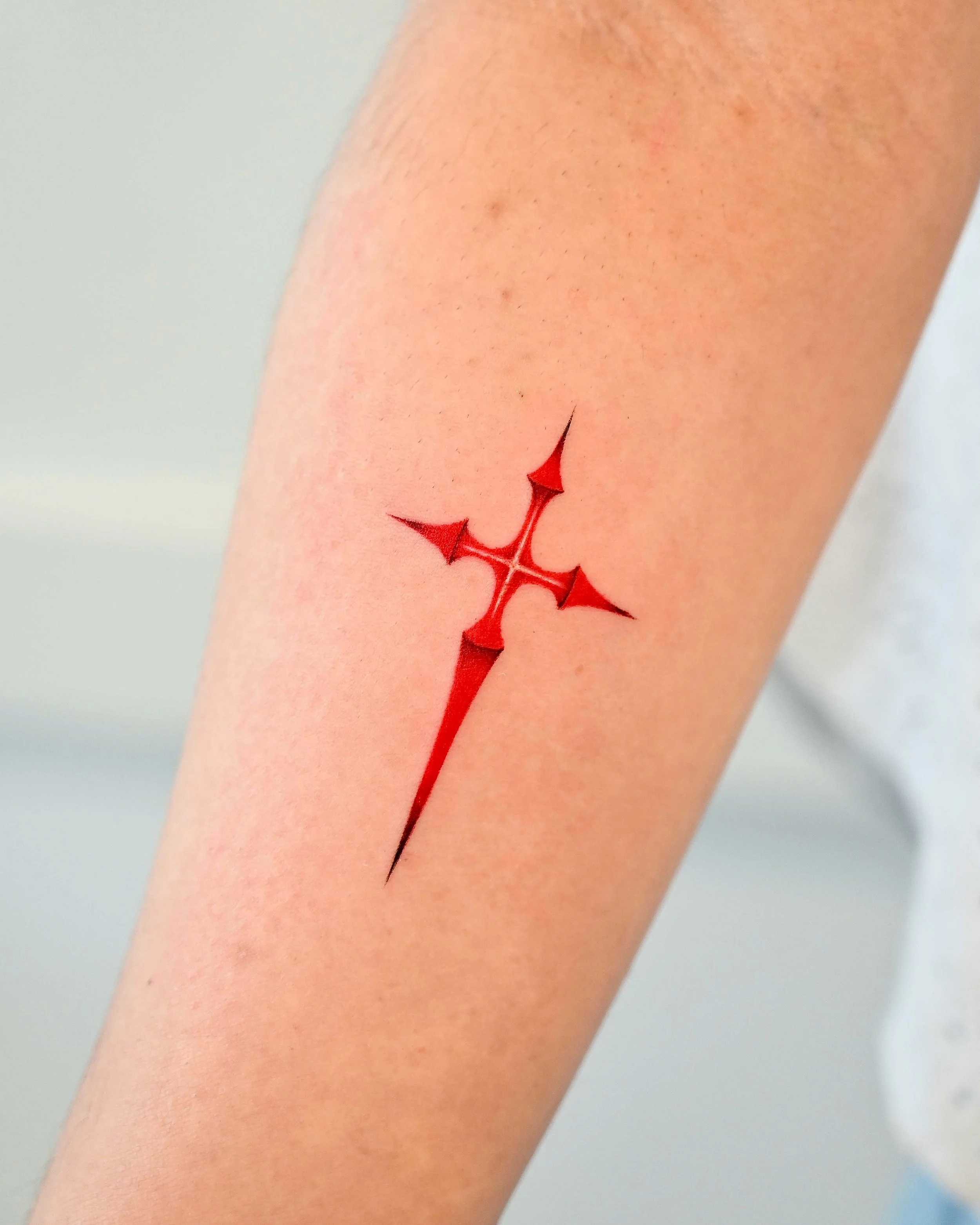 Red abstract cross arm tattoo by Megink.