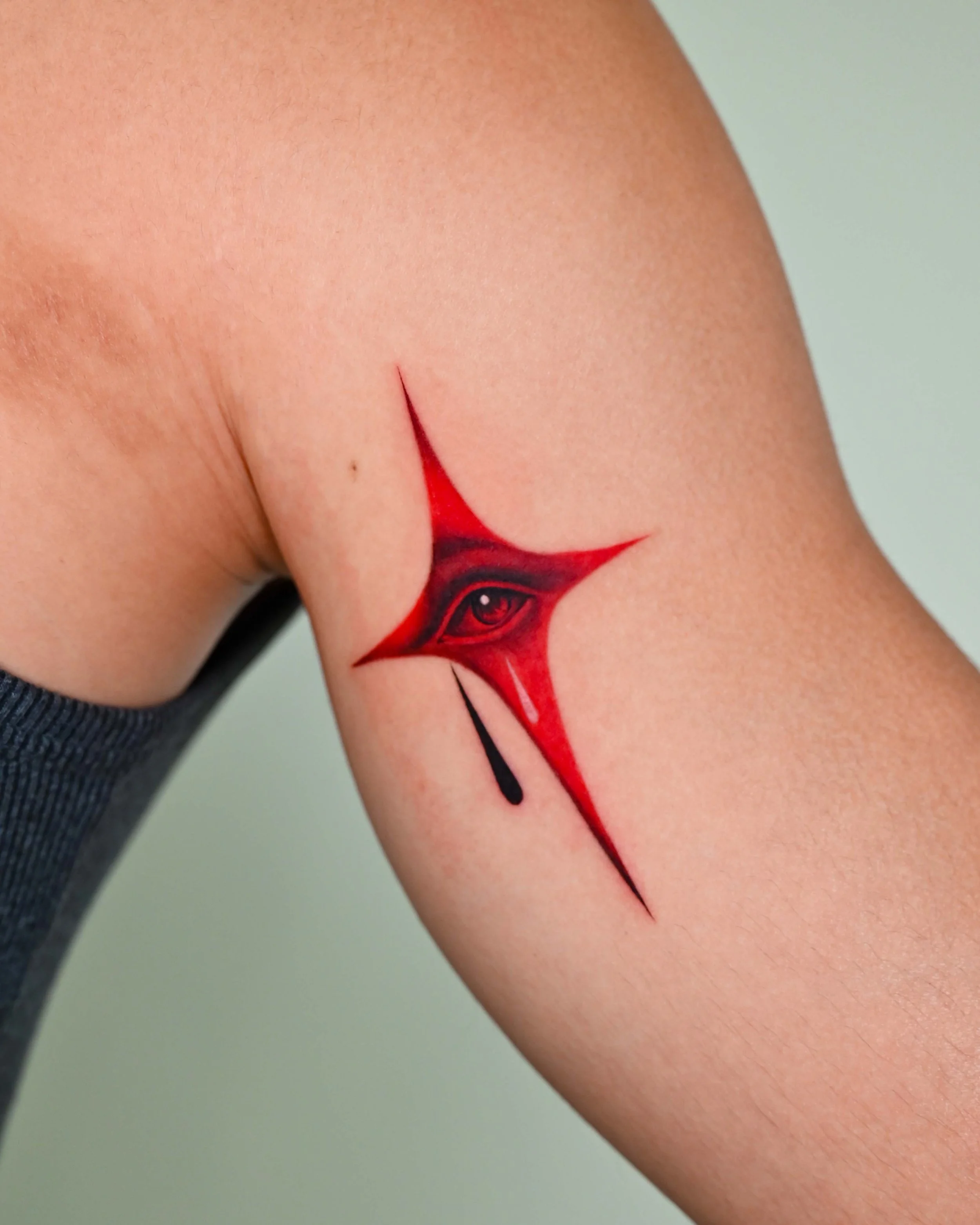 Red and black abstract star tattoo with crying eye by Megink.