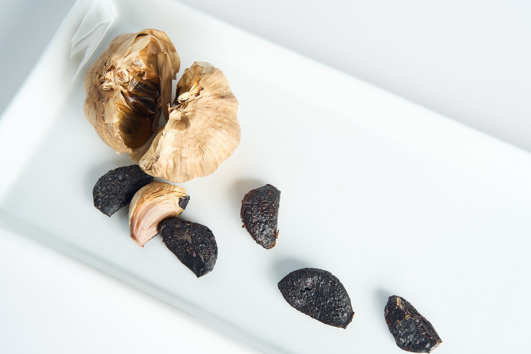 Charcoal and roasted garlic cloves on a white plate.