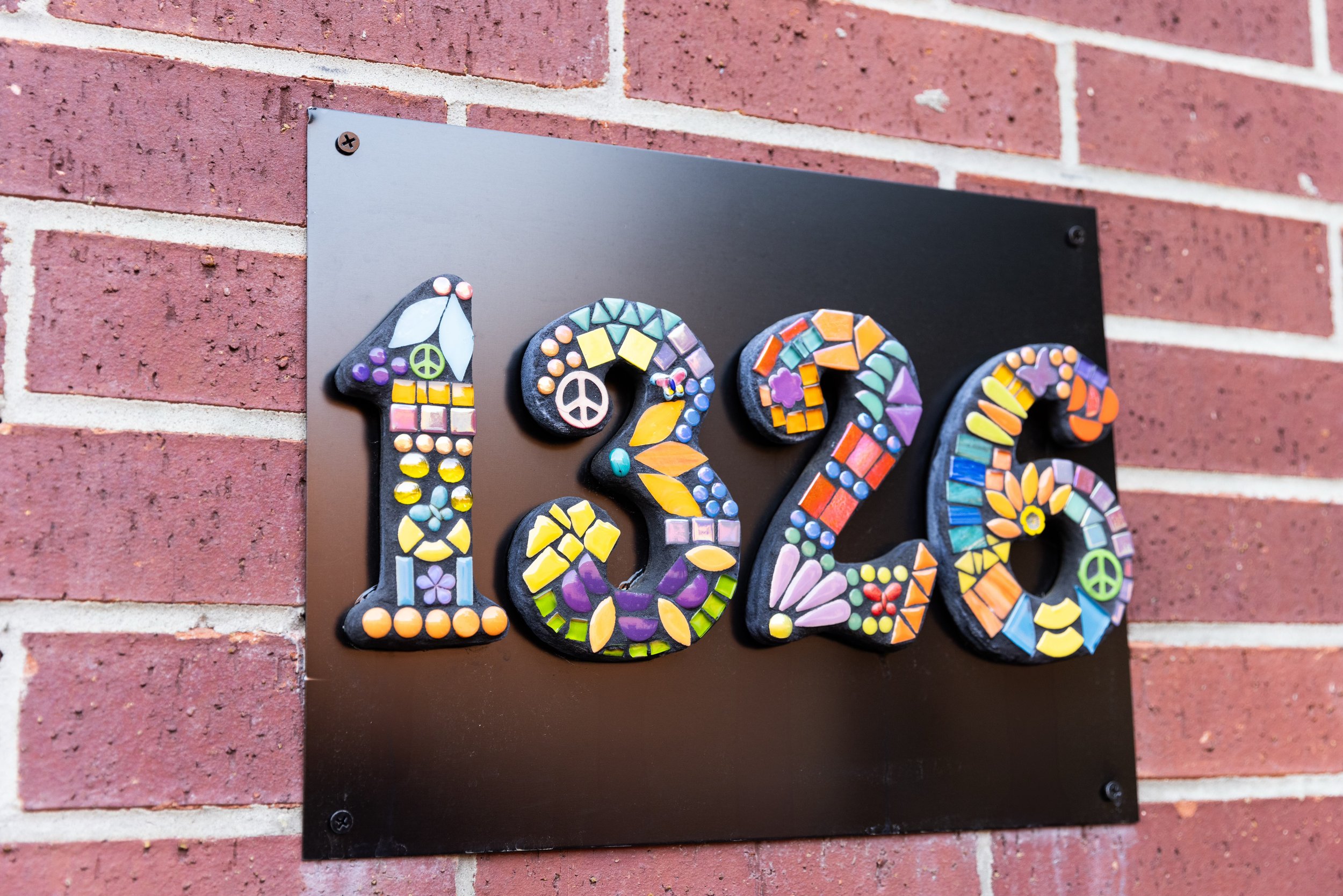 Mosaic house number 1326 on a brick wall