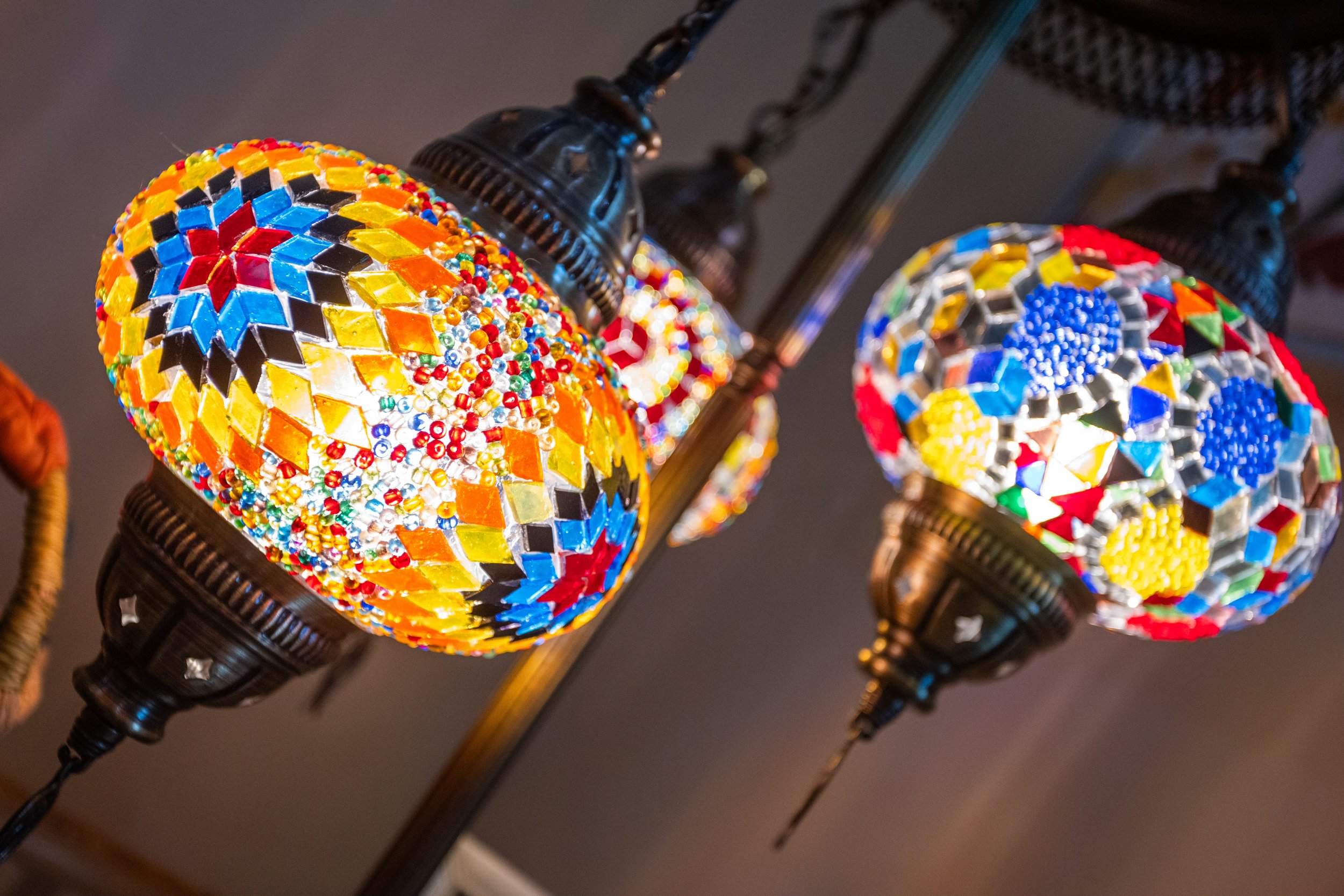 Colorful mosaic glass lamps hanging from a metal fixture.
