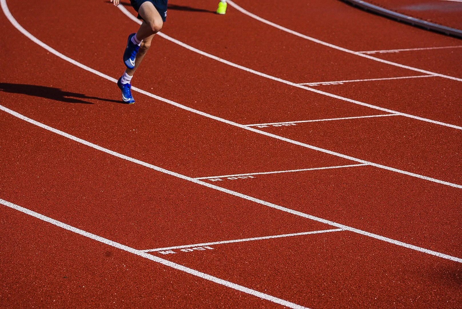 Athlete sprinting on a red running track with white lane markings.
