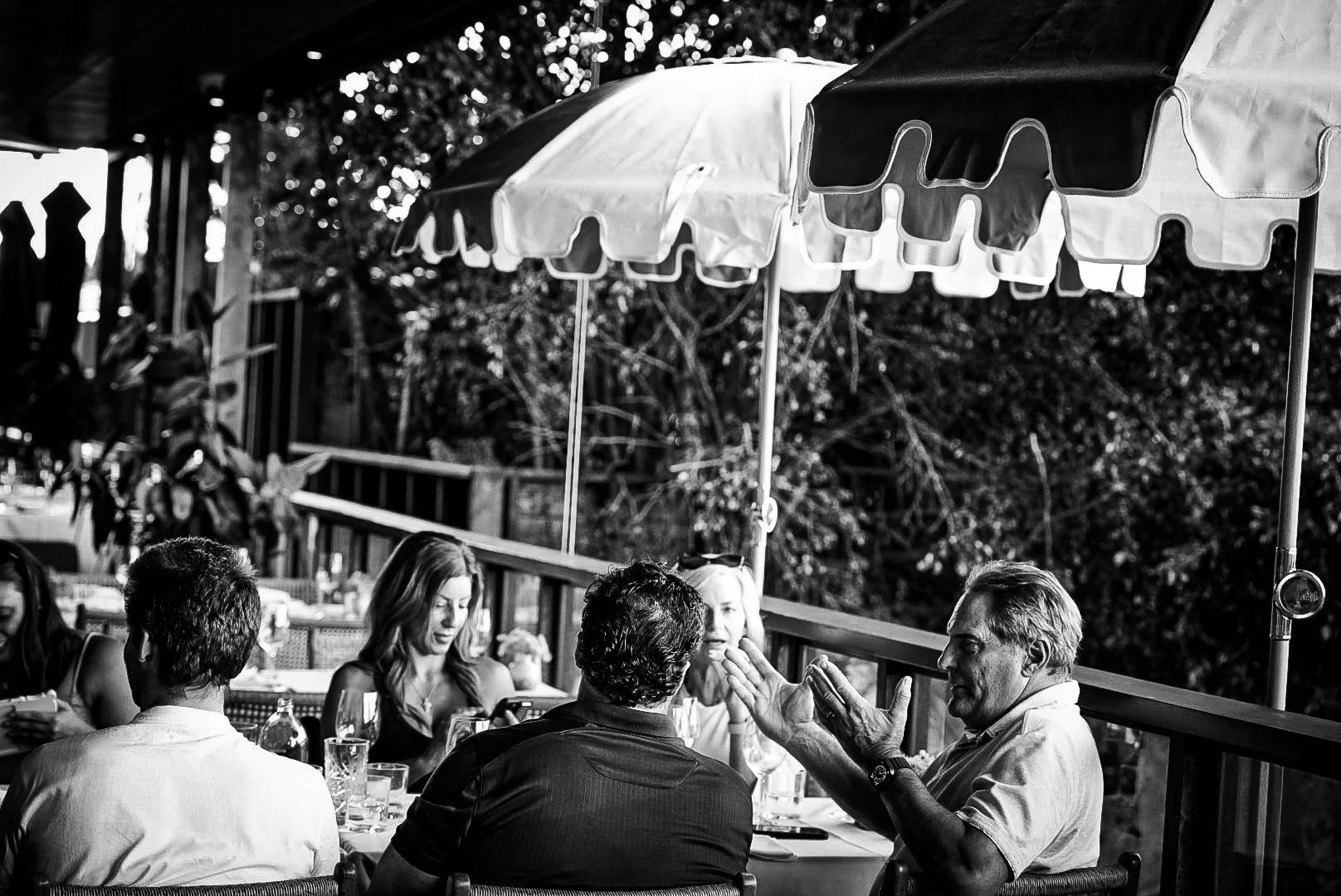 People dining outdoors under umbrellas at a restaurant during evening or daylight.