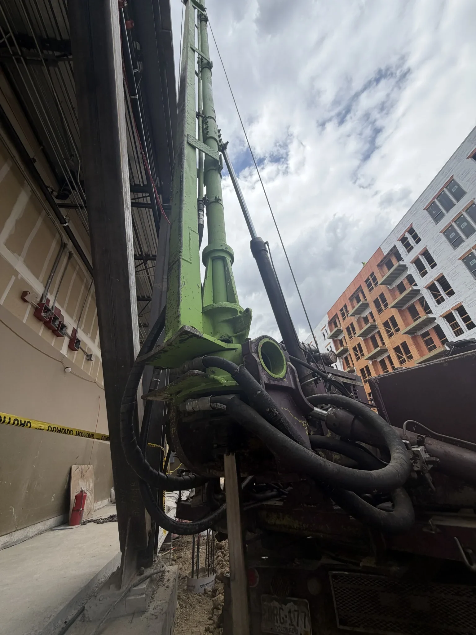 Small-diameter foundation drilling alongside an existing structure with limited equipment clearance.