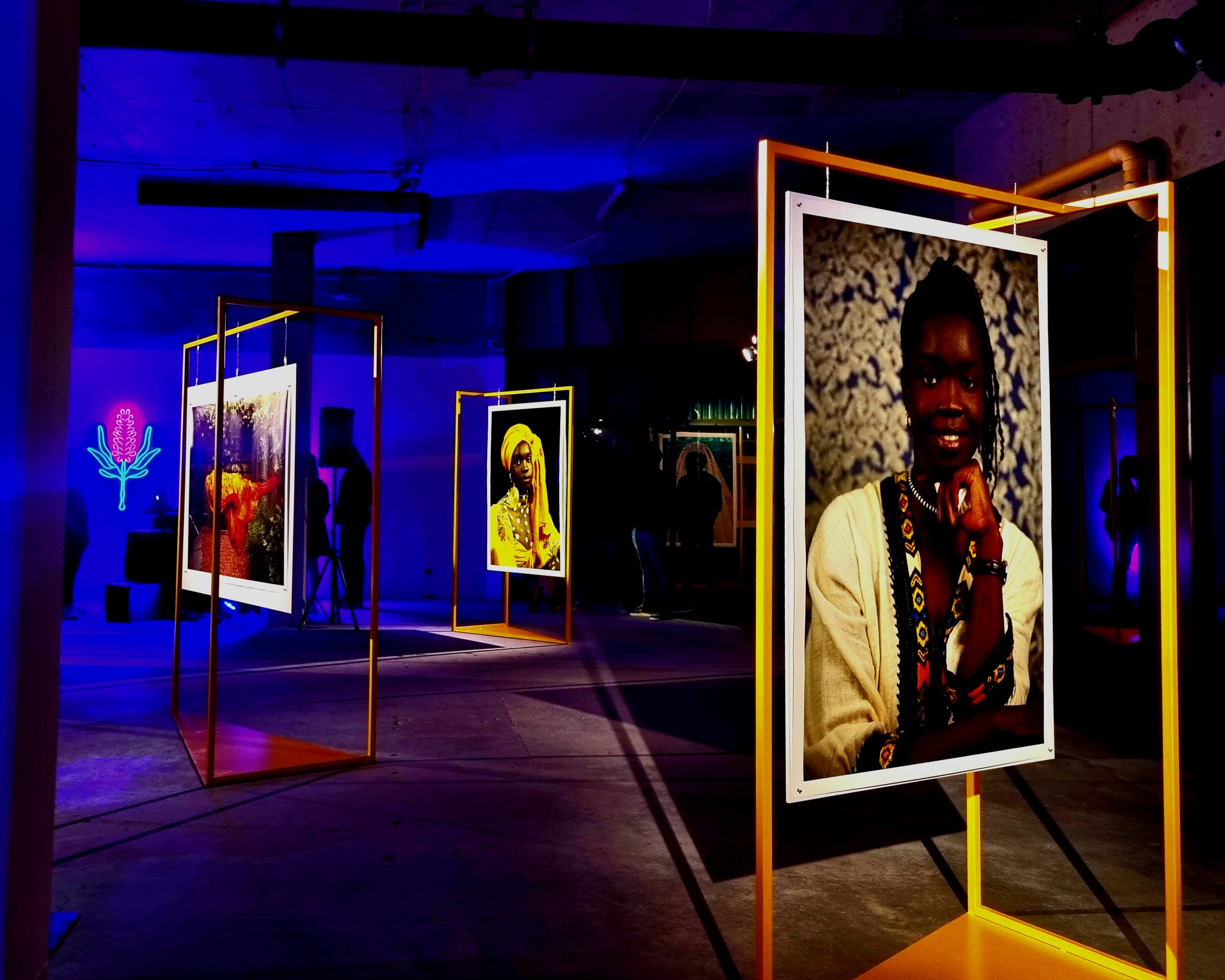 Art gallery installation with colorful framed photographs and neon lighting.