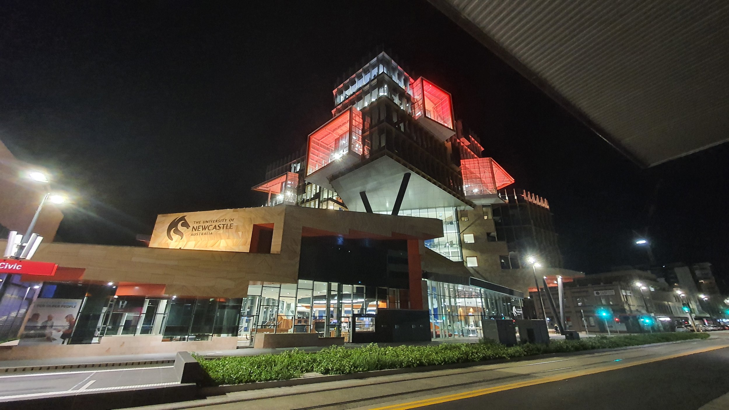 Night view of University of Newcastle building with illuminated red and glass architecture in Newcastle, Australia.