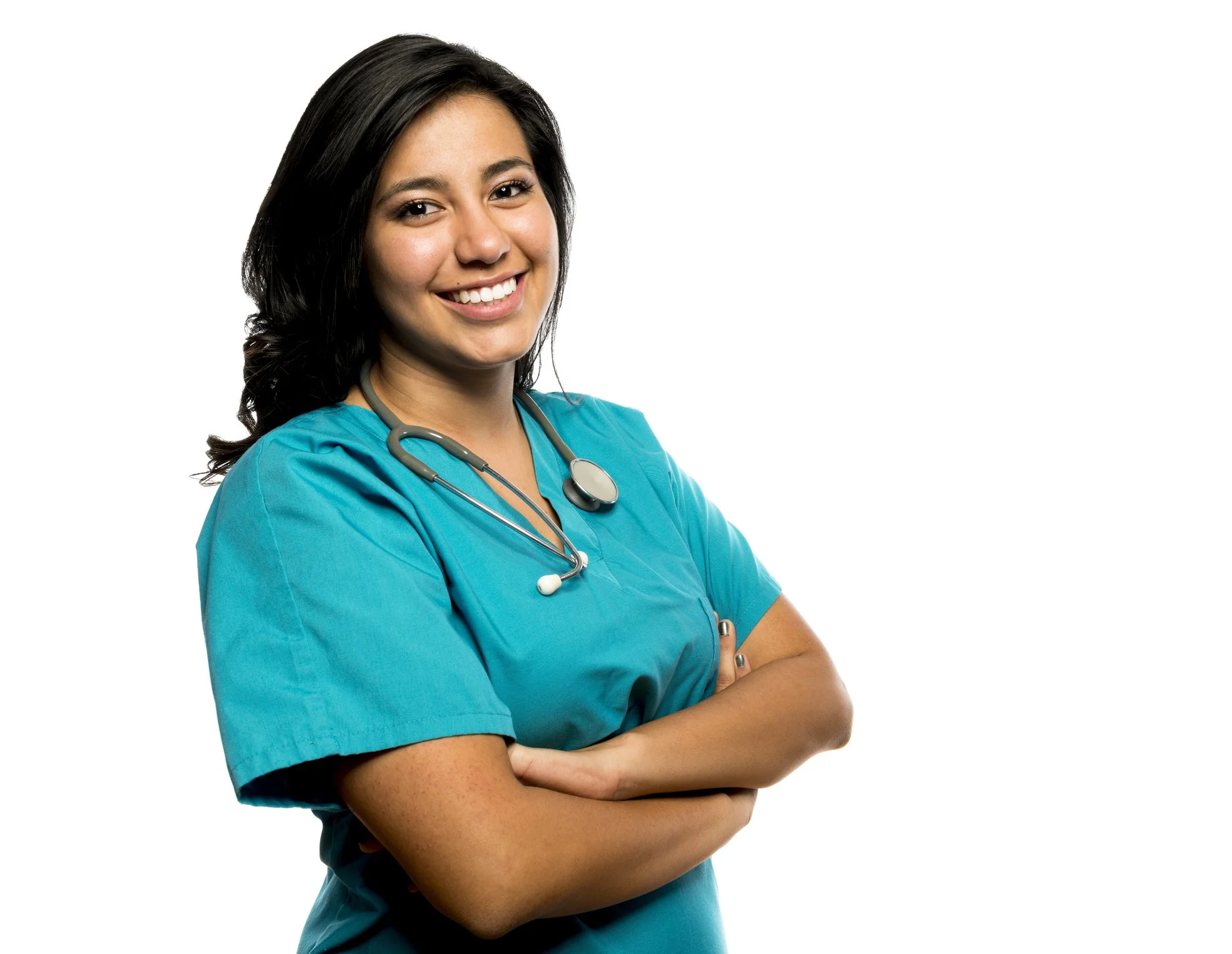 Young female nurse in blue scrubs with stethoscope smiling, arms crossed, against white background.