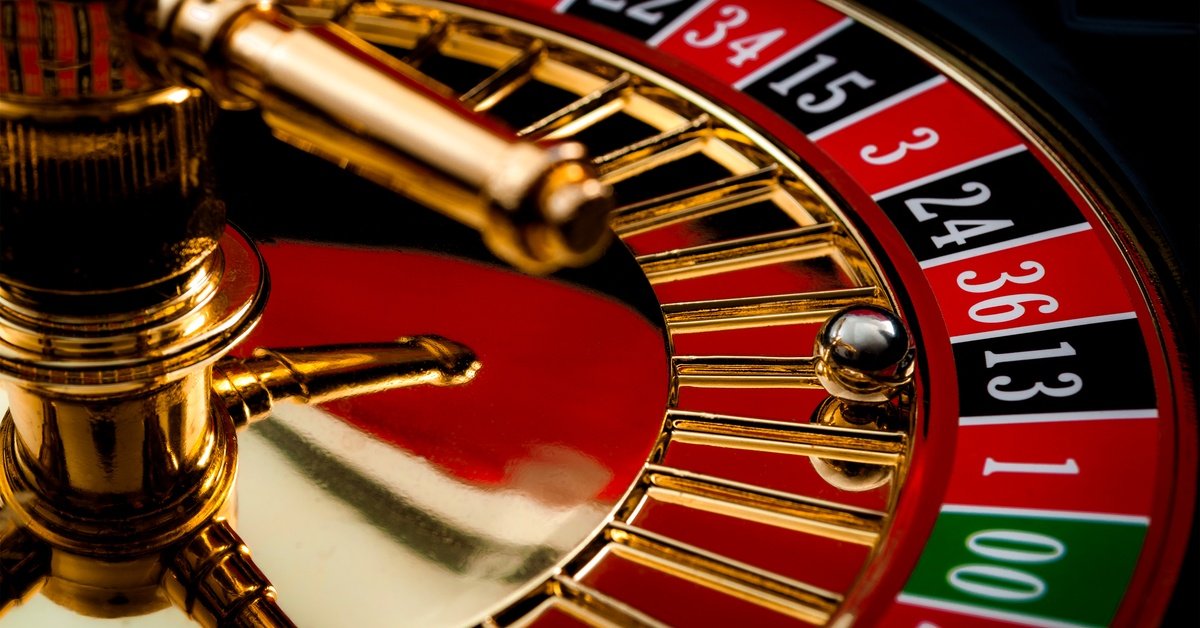 Close-up of a shiny roulette wheel marked with alternating red and black numbered slots. The ball rests on 13 black.