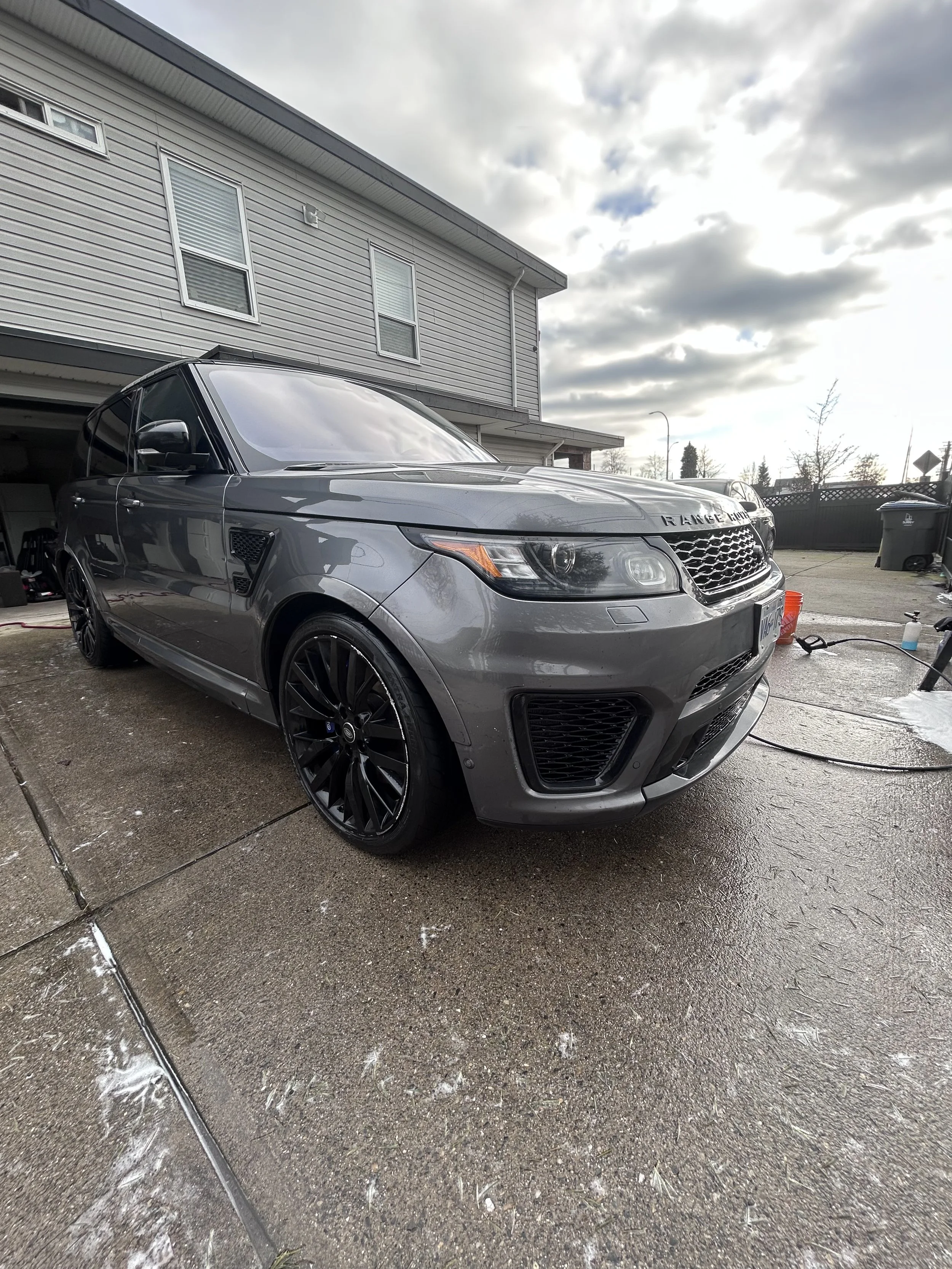 Gray Range Rover parked on a concrete driveway in front of a house.