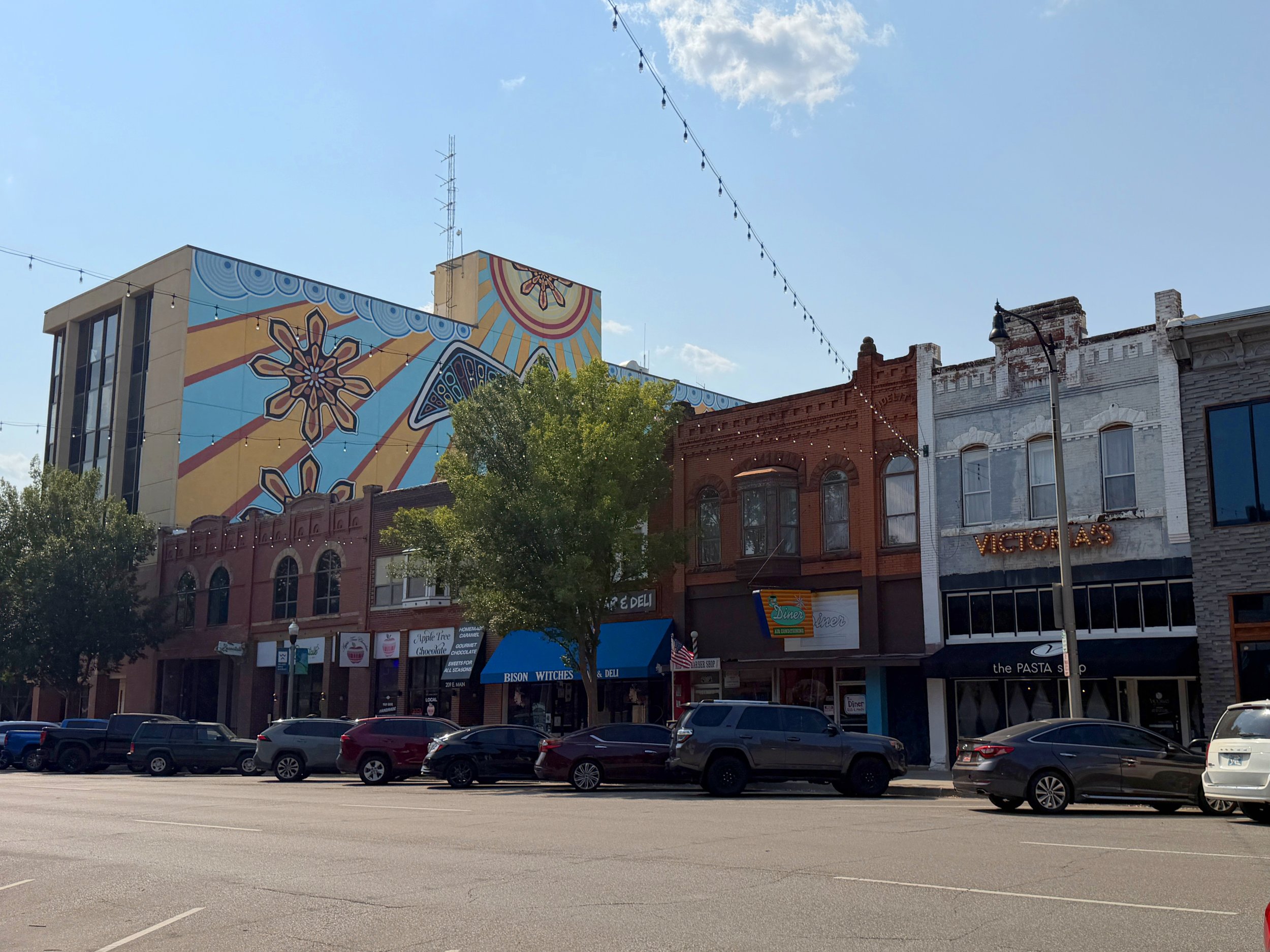Historic downtown Norman, Oklahoma, featuring colorful murals and local businesses along Main Street