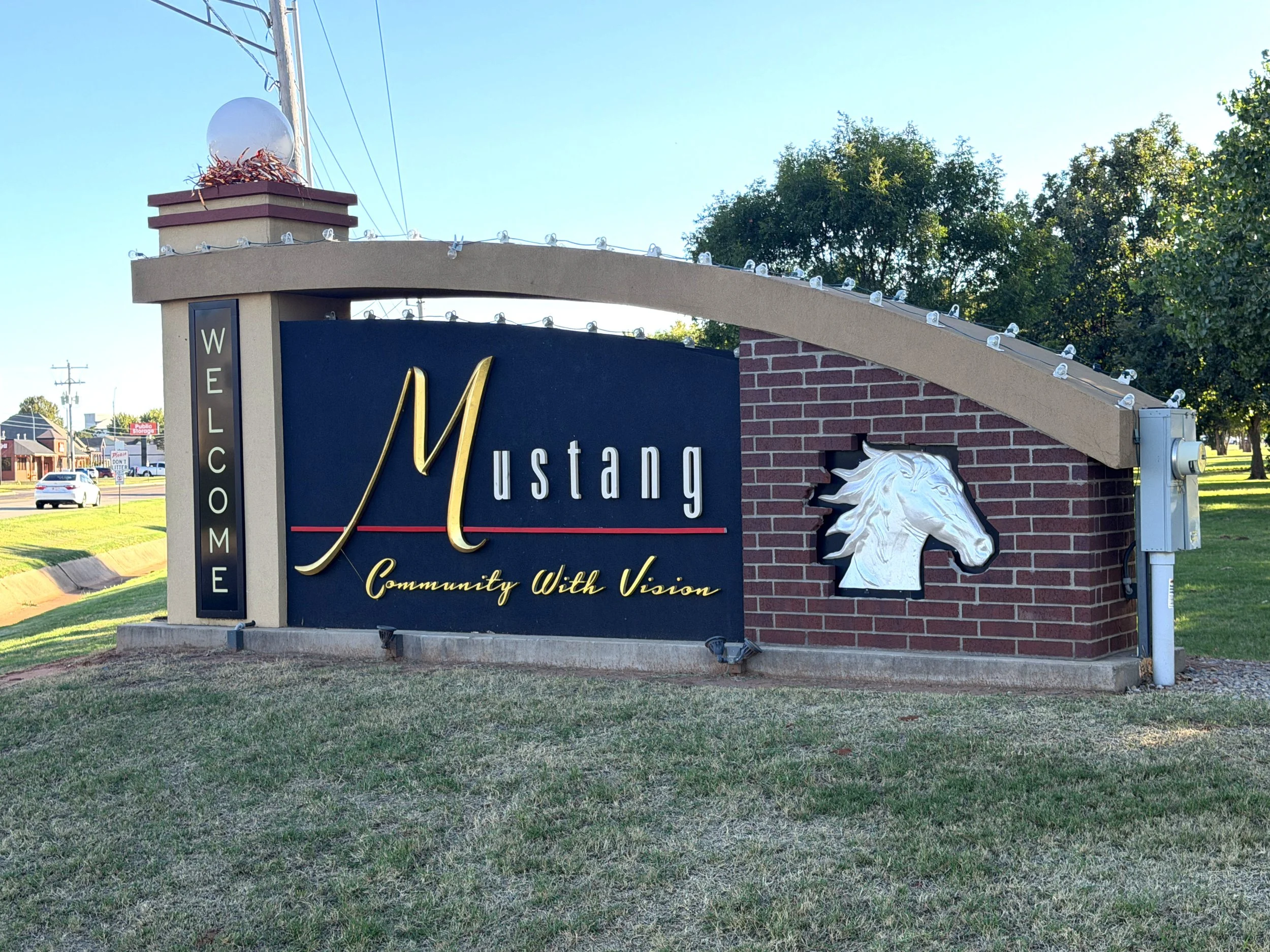Welcome to Mustang, Oklahoma sign featuring the city's horse emblem and Community With Vision motto