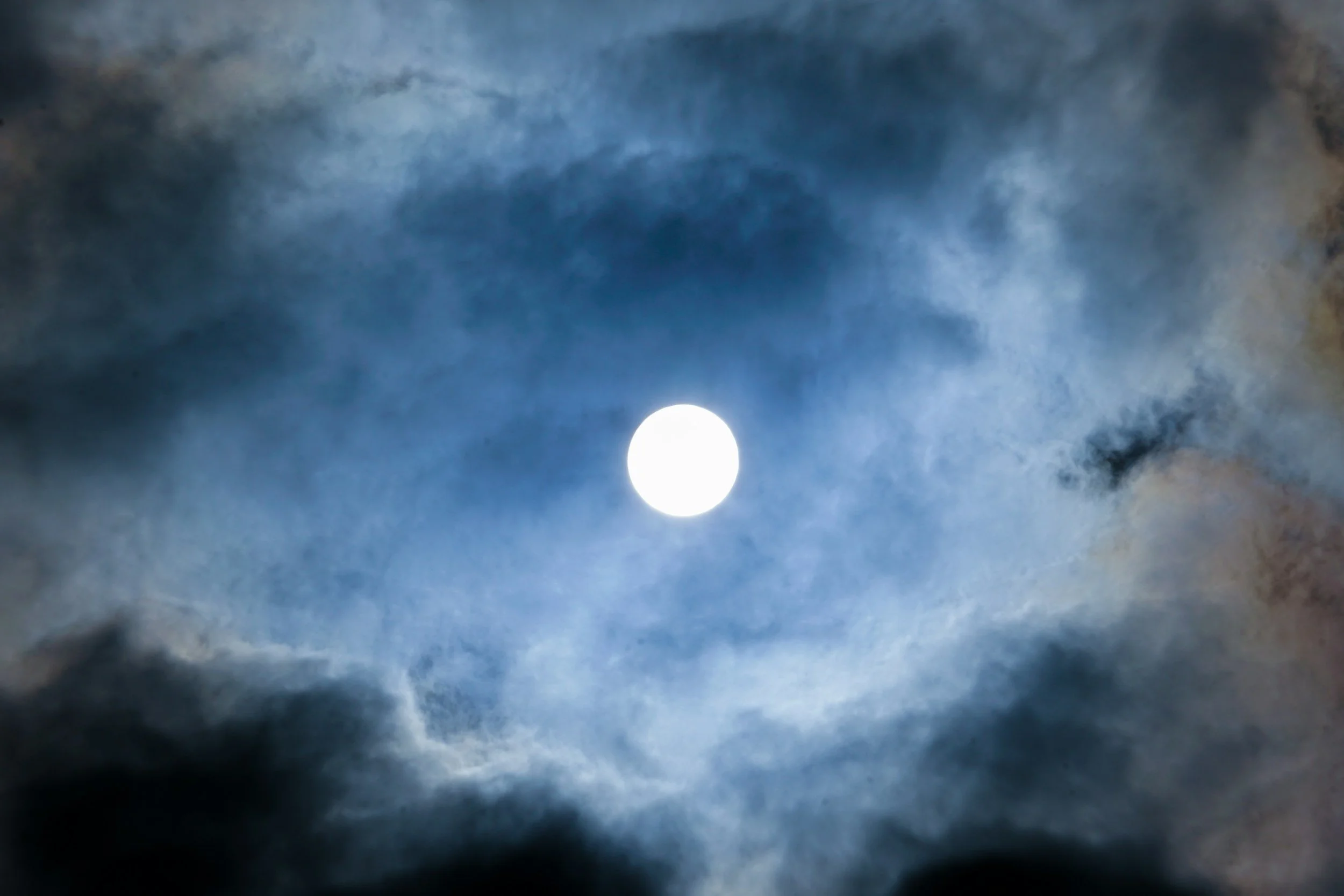 The image shows a bright full moon in a cloudy night sky.