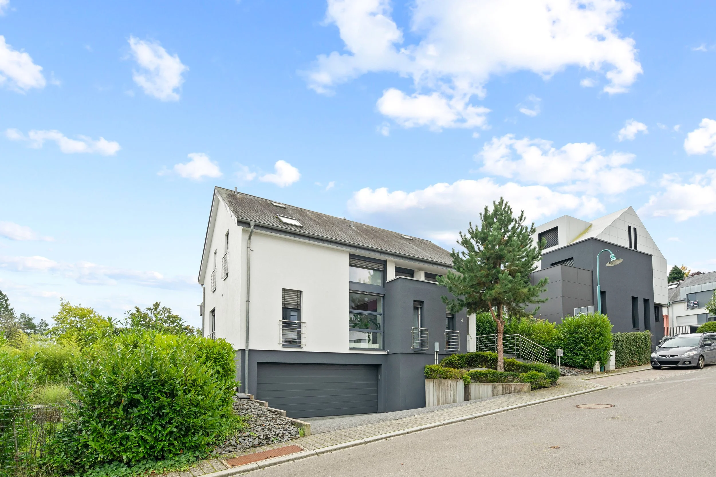 Maisons modernes avec jardins et voitures garées dans une rue résidentielle