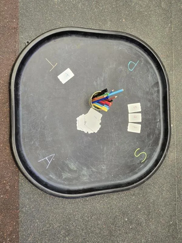 Desk with clock face made of papers, pens, and labeled index cards for each hour from 1 to 12, with the center holding colored pens and pencils.