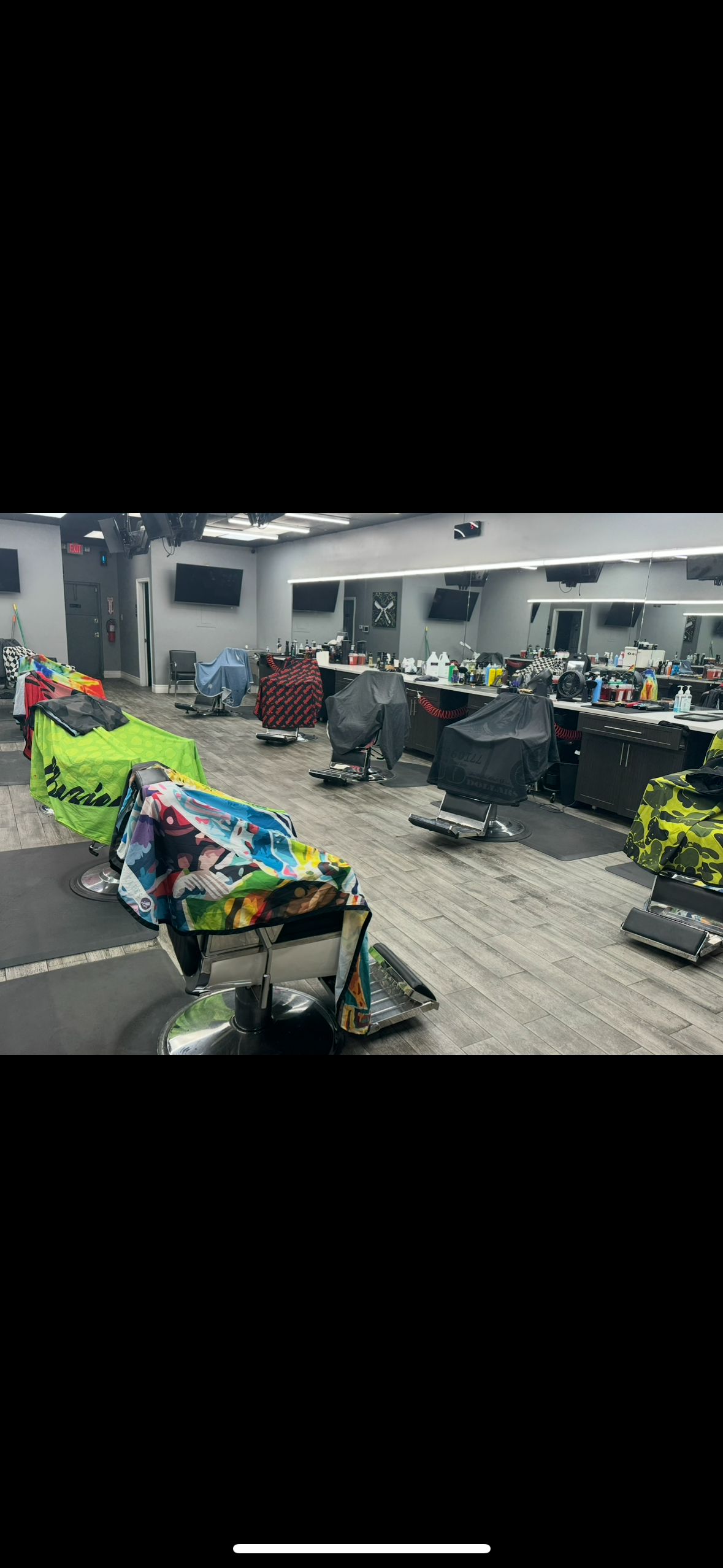 Barbershop with chairs covered in colorful towels, mirrors on wall, and various barber tools and products on counter.