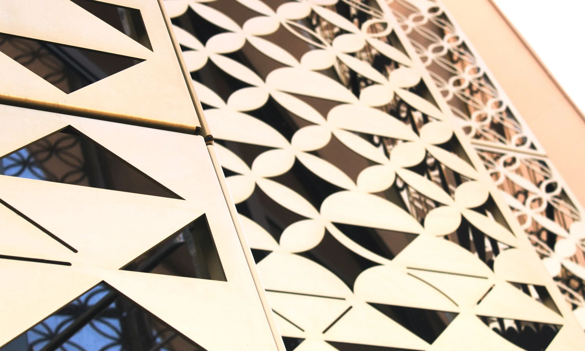 Close-up of a decorative metal surface with a geometric pattern of interlocking circles and diamond shapes, painted in a light color.