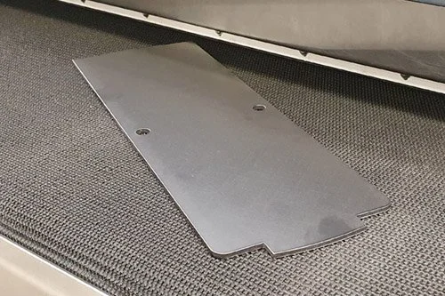 A metal panel lying on a conveyor belt.