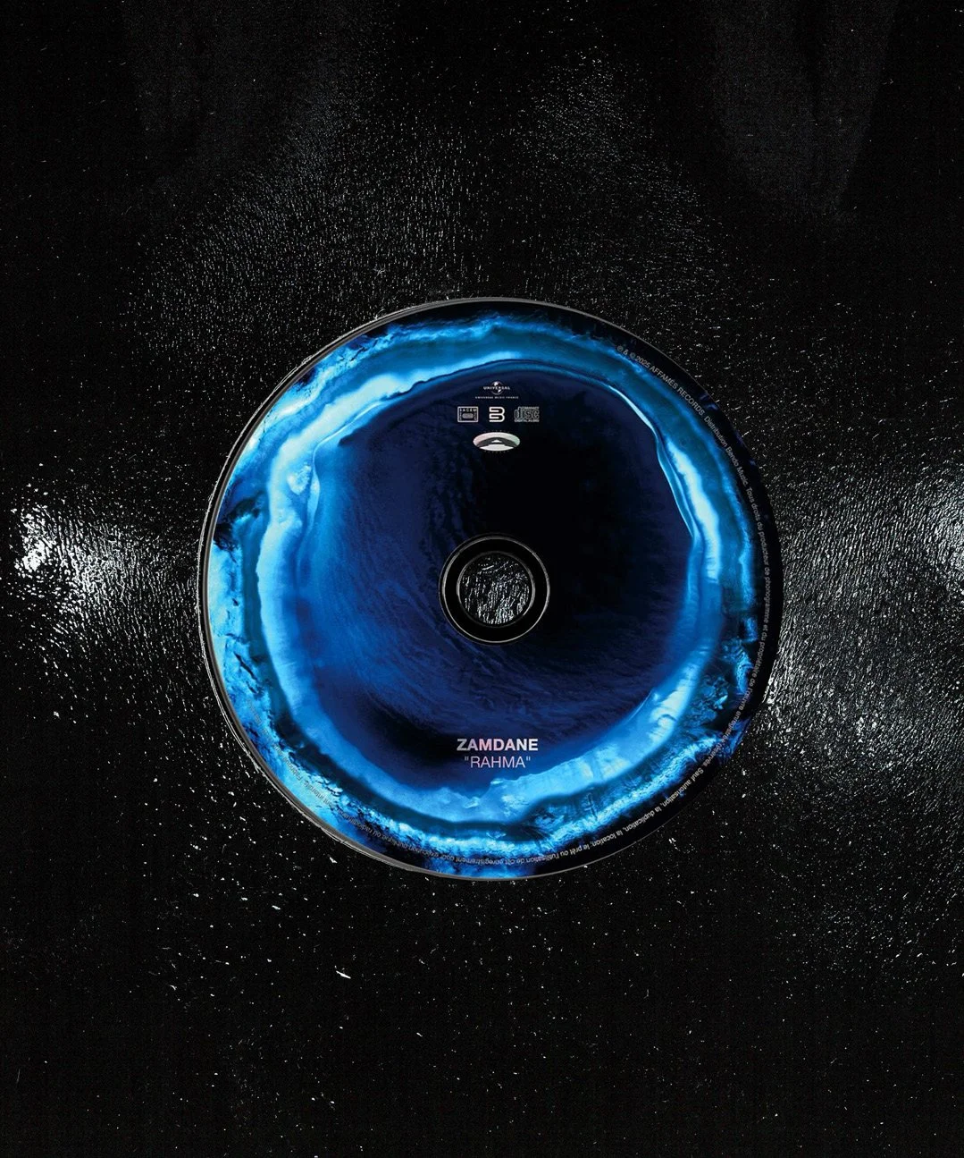 Vue aérienne d'un disque en vinyle avec une image de ciel et d'océan, et le texte 'ZAMDANE 'RAHMA'' en bas.
