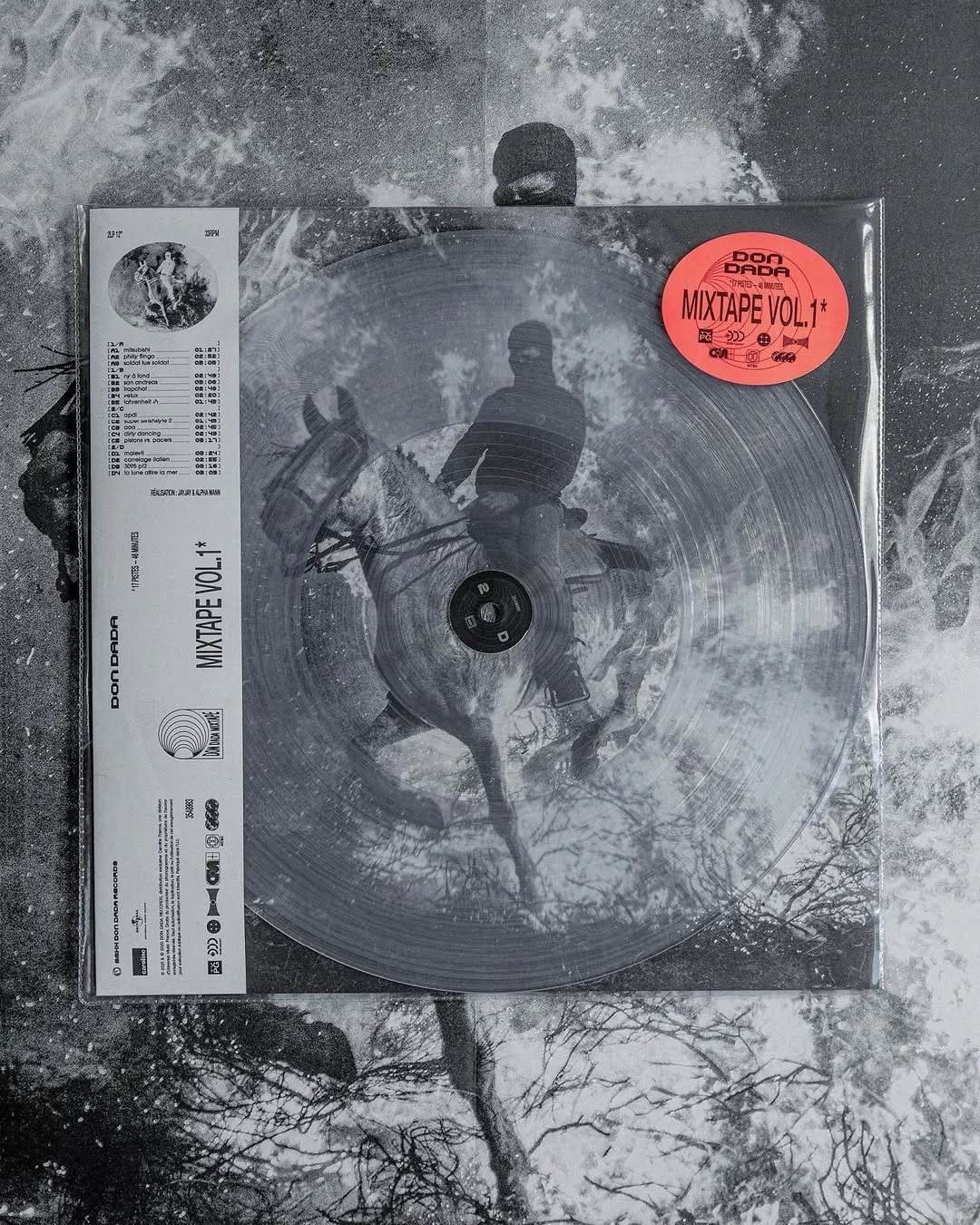 Un vinyle transparent avec une image en noir et blanc d'un homme à cheval dans une forêt, avec des labels rouges et blancs indiquant 'MIXTAPE VOL.1' et des informations en français.