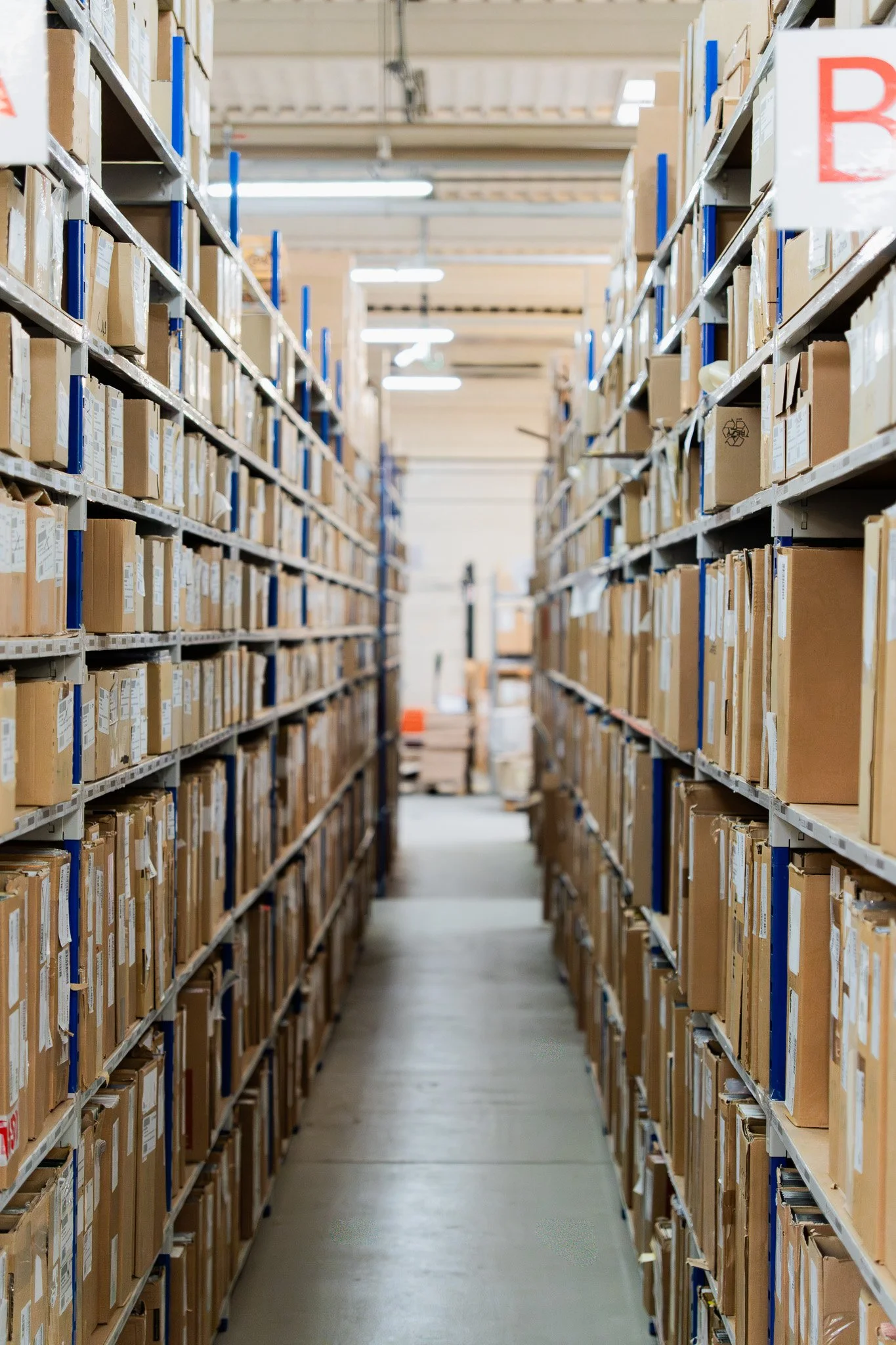 Allées d'étagères remplies de boîtes en carton dans un entrepôt.