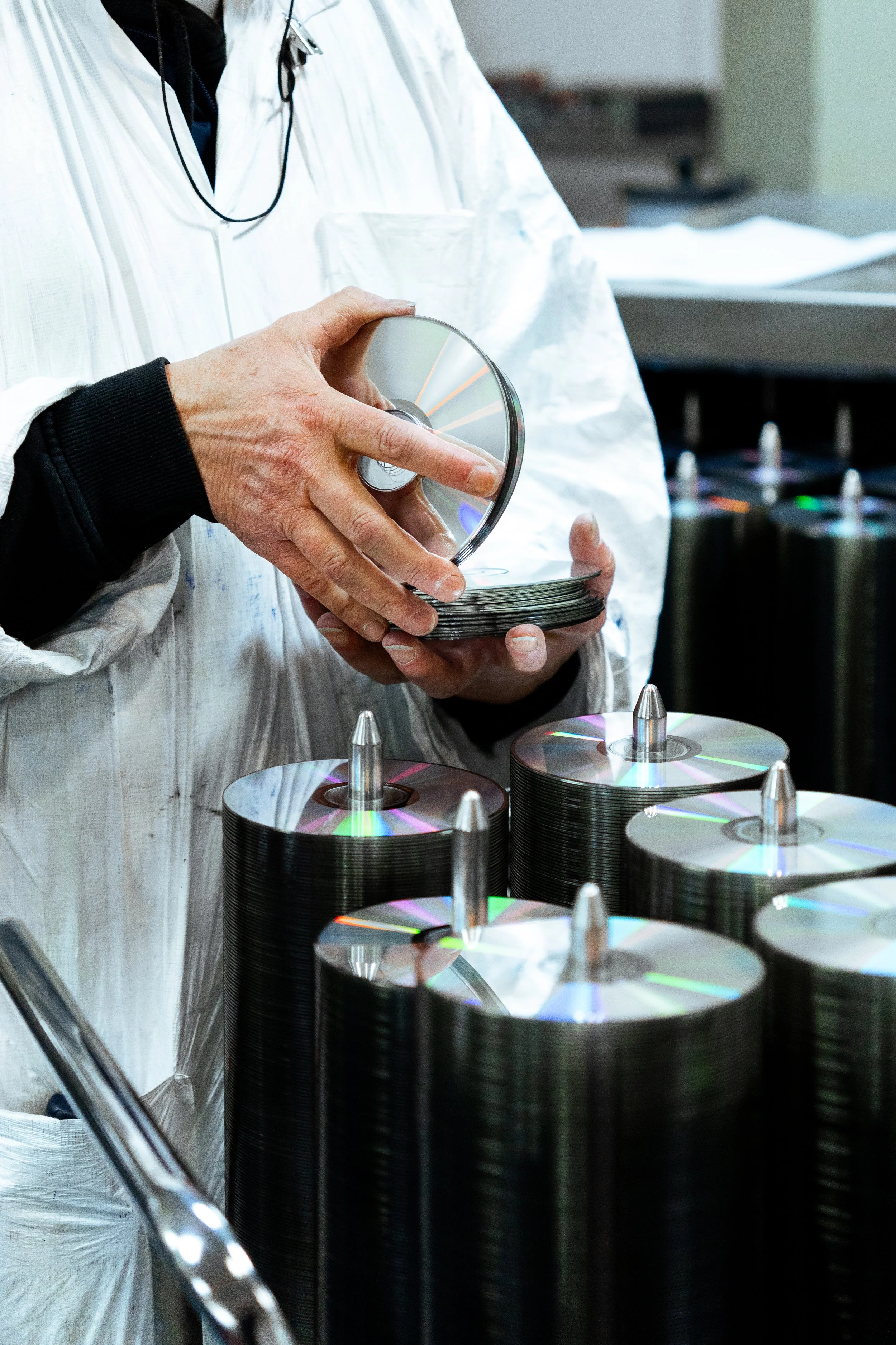 Une personne manipule des disques compacts (CD) dans un environnement industriel ou de fabrication.