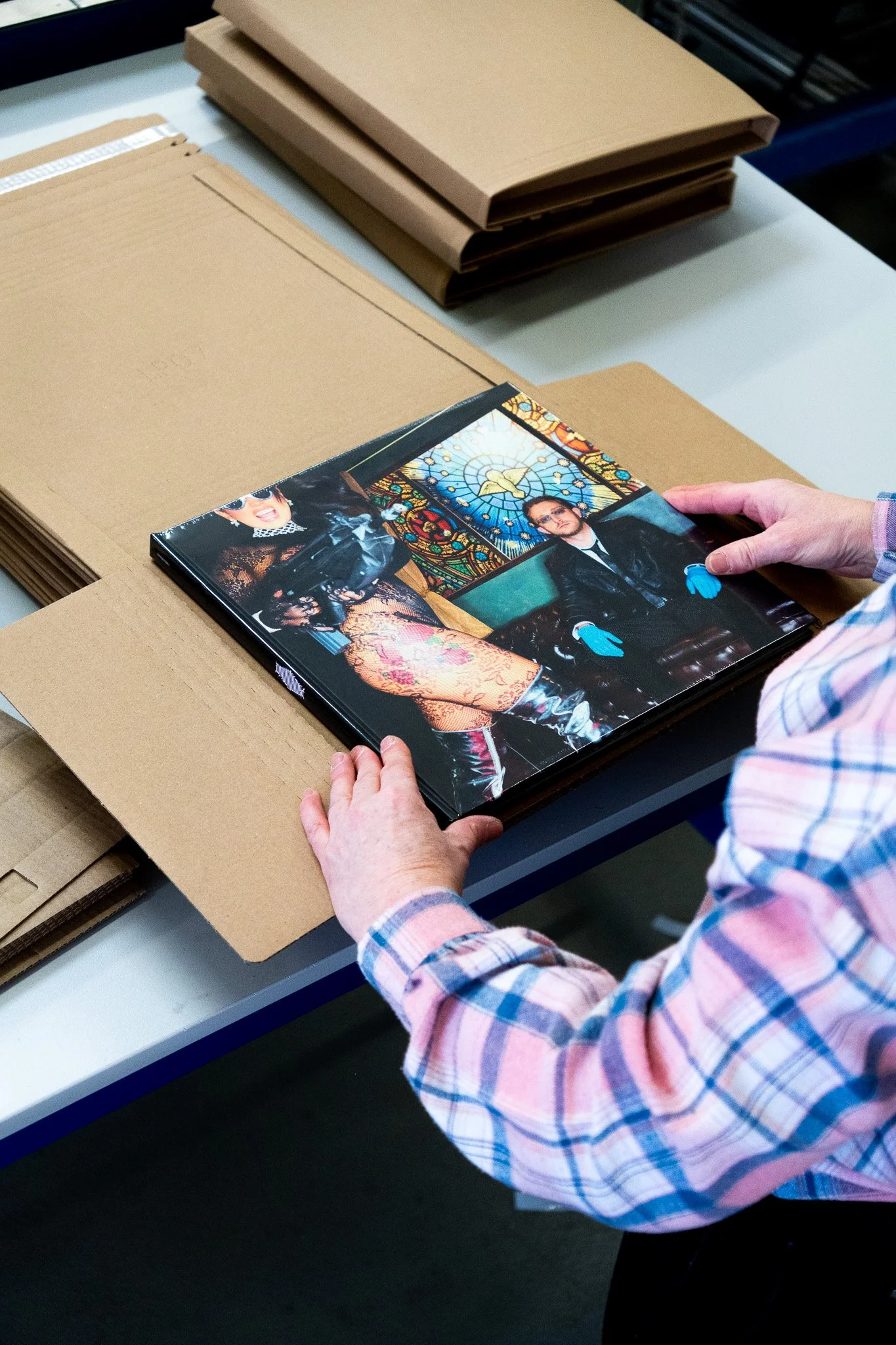 Une personne manipulant une photographie dans un centre de fabrication, avec des sacs en carton vides sur une table.