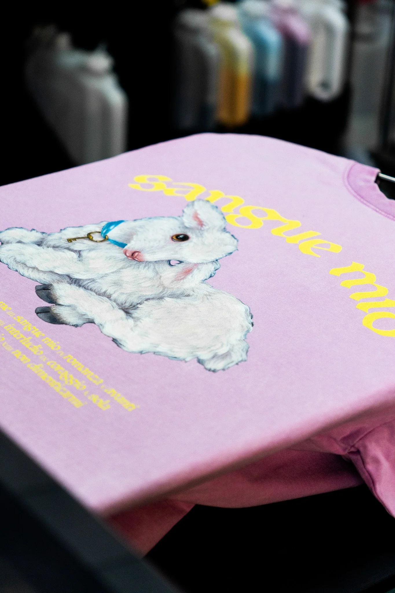 T-shirt rose clair avec une illustration d'un hamster blanc portant un collier bleu, et du texte en jaune "some more".