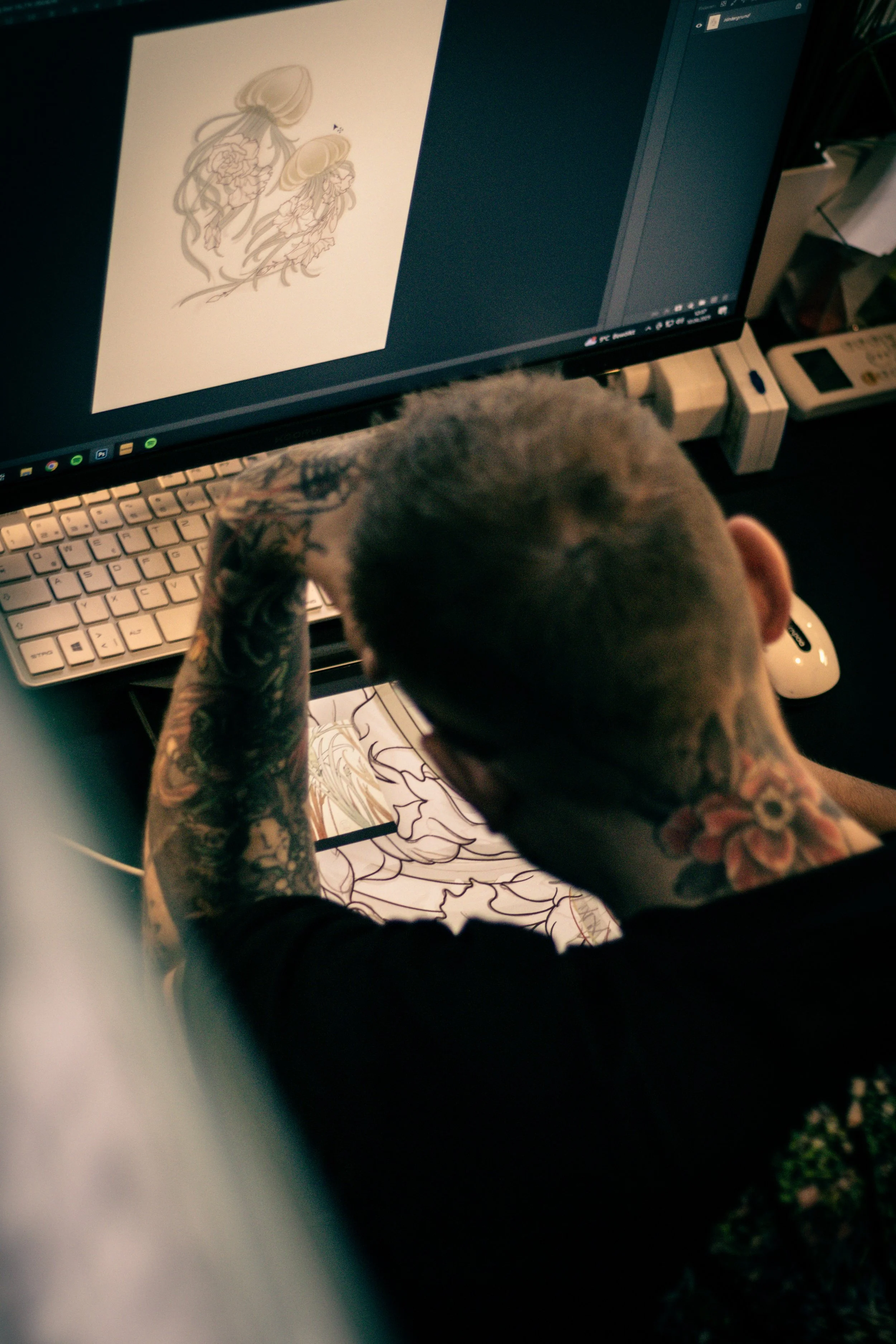 Person mit Tattoos am Arm arbeitet an einer digitalen Zeichnung von Meerestieren, vermutlich Quallen, auf einem Computerbildschirm.