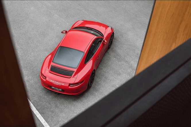Voiture rouge de sport vue du dessus, stationnée dans un parking.