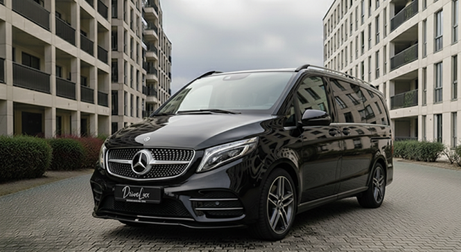 Van noir Mercedes-Benz stationnement dans un parking résidentiel, entouré de bâtiments modernes.