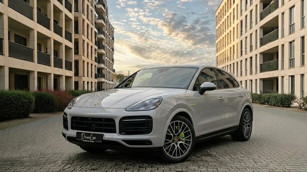 Voiture blanche électrique de luxe SUV stationnée entre deux immeubles résidentiels, avec un ciel nuageux au coucher du soleil.