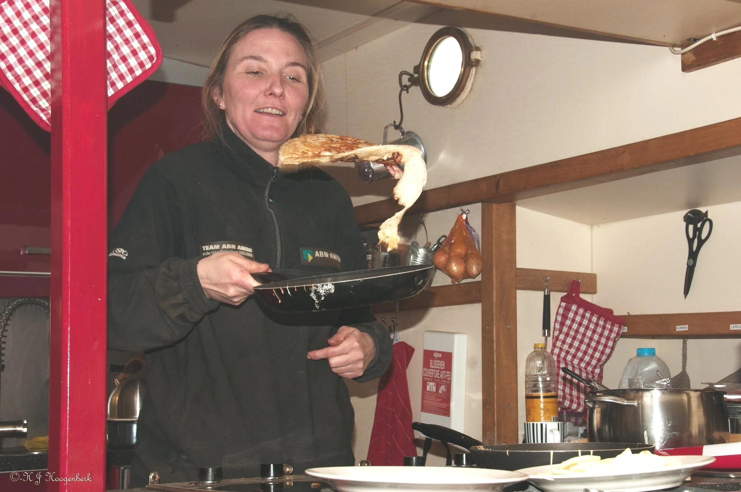 Vrouw bakt een pannenkoek in een koekenpan in een keuken.