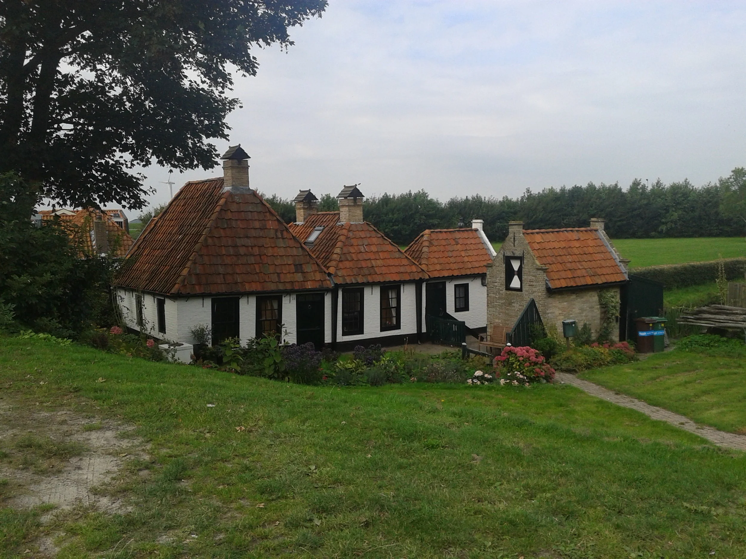 Historische huisjes met rode daken en witte muren in een landelijke omgeving.