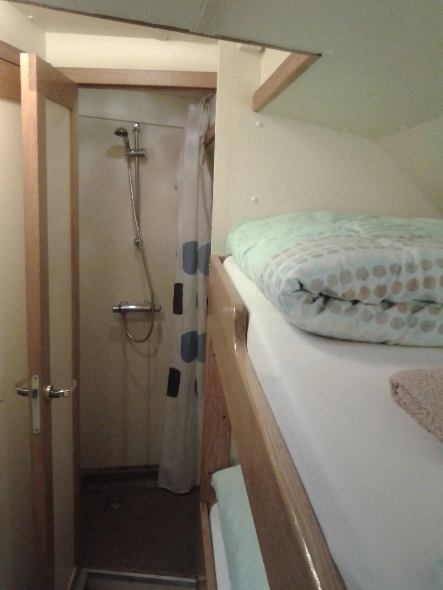 Een kleine slaapruimte met een stapelbed en een douchecabine met een douchegordijn.