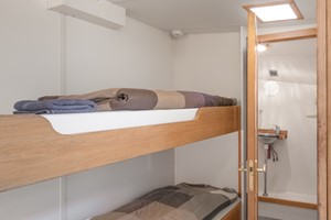 Kleine slaapkamer met stapelbedden en een badkamerdeur.