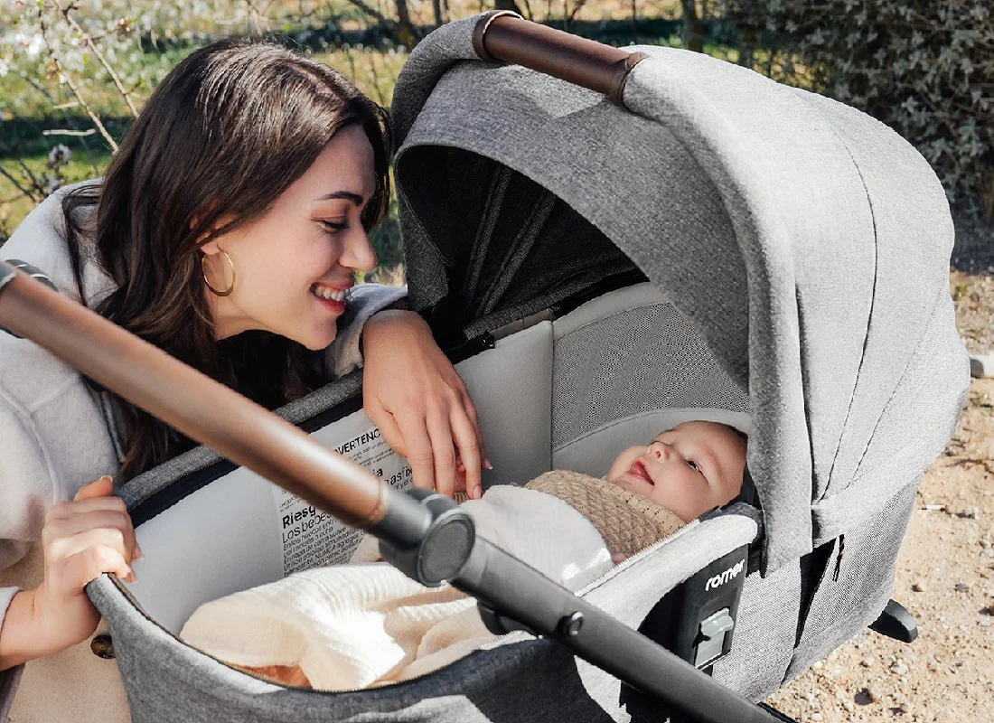 A woman looking at a baby in a bassinet stroller.jpg