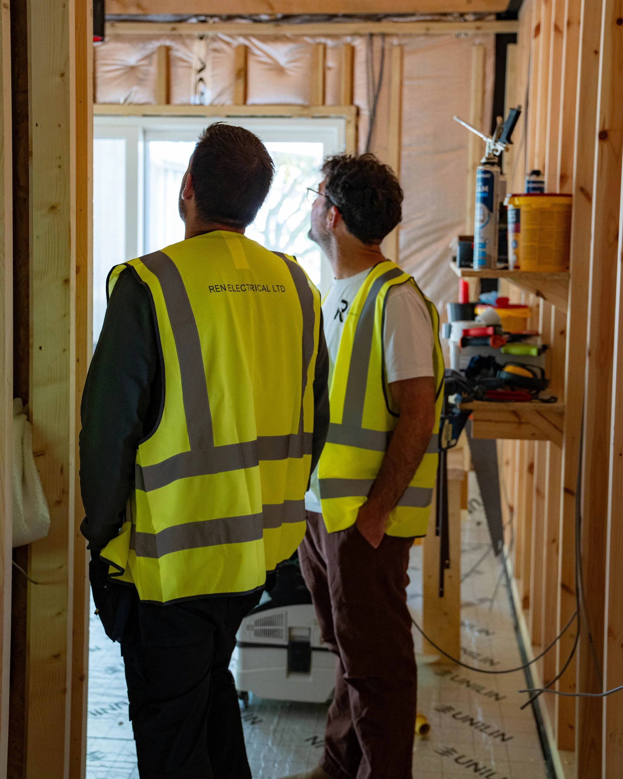 Two team members from REN Electrical wearing high vis looking up at a ceiling.