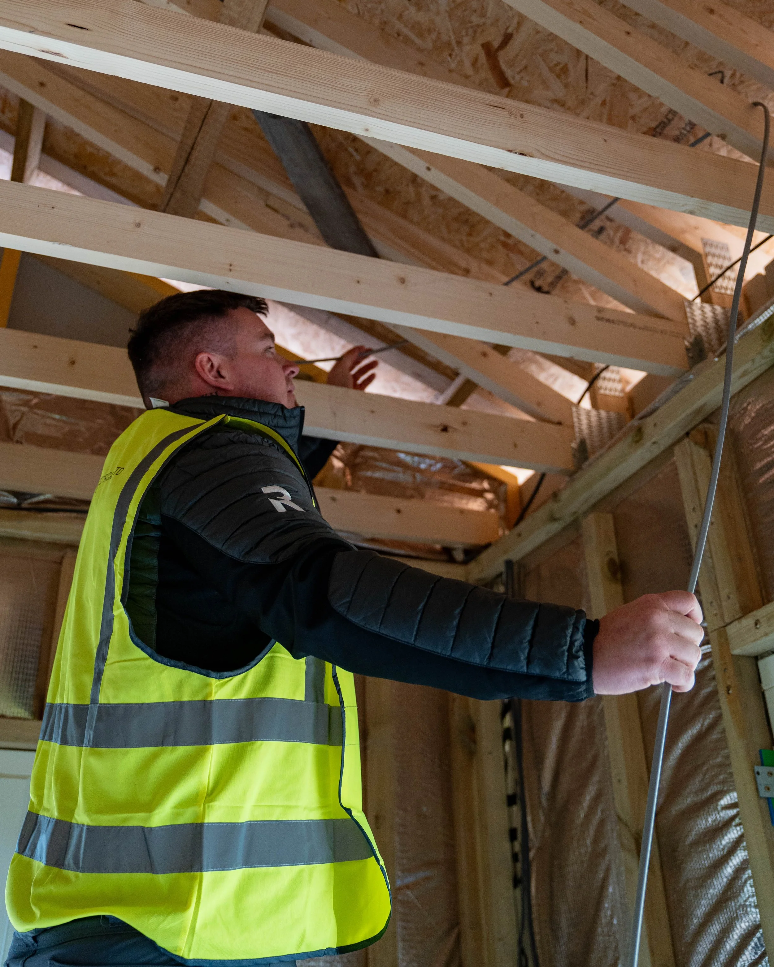 Team member in REN Electrical branded clothes and high vis up a ladder