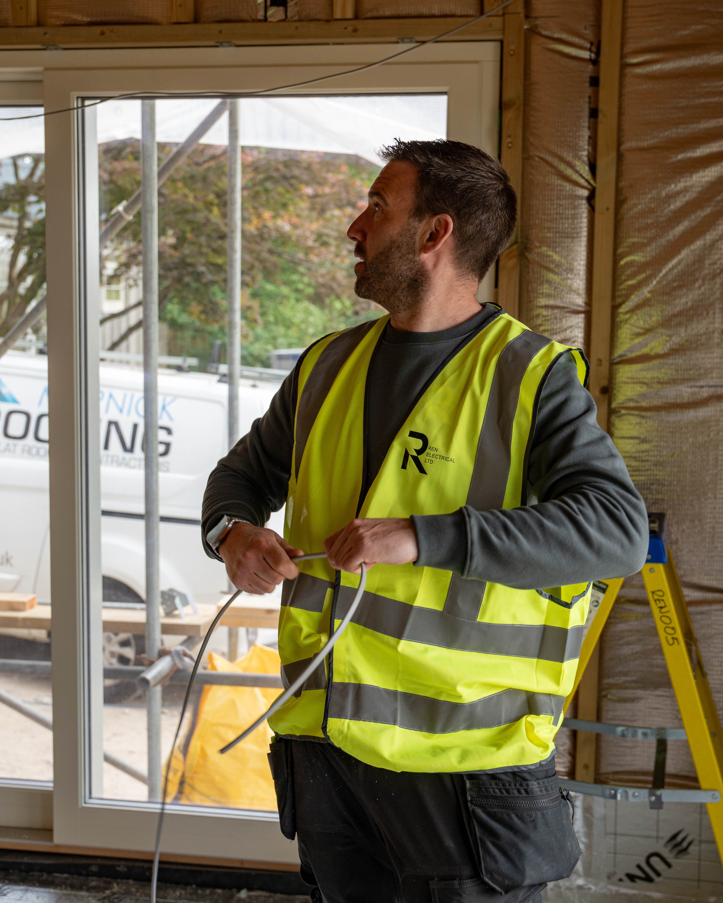 Team member holding a cable wearing REN Electrical branded high vis