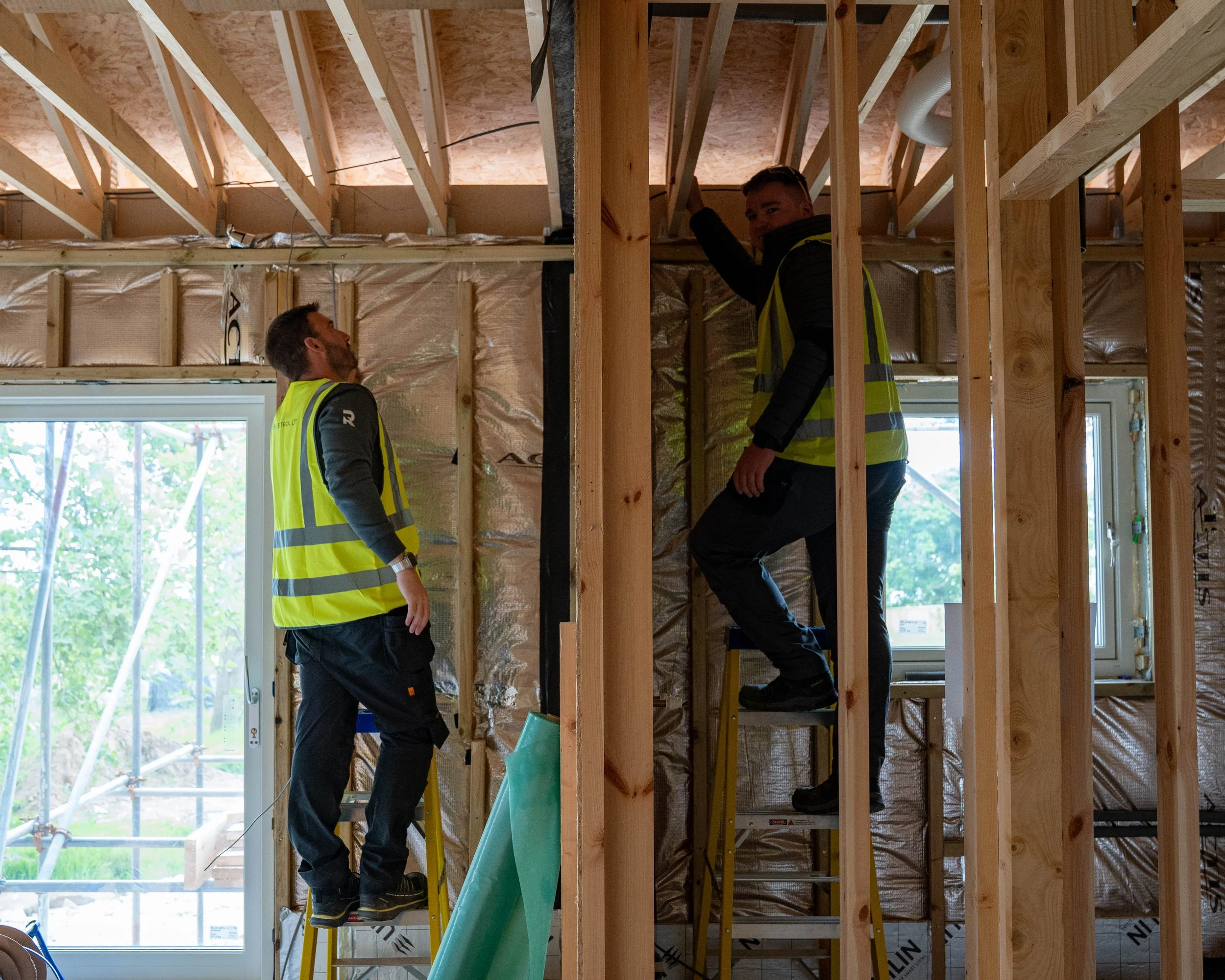 Two team members from REN Electrical, inside on a job, both on a ladder