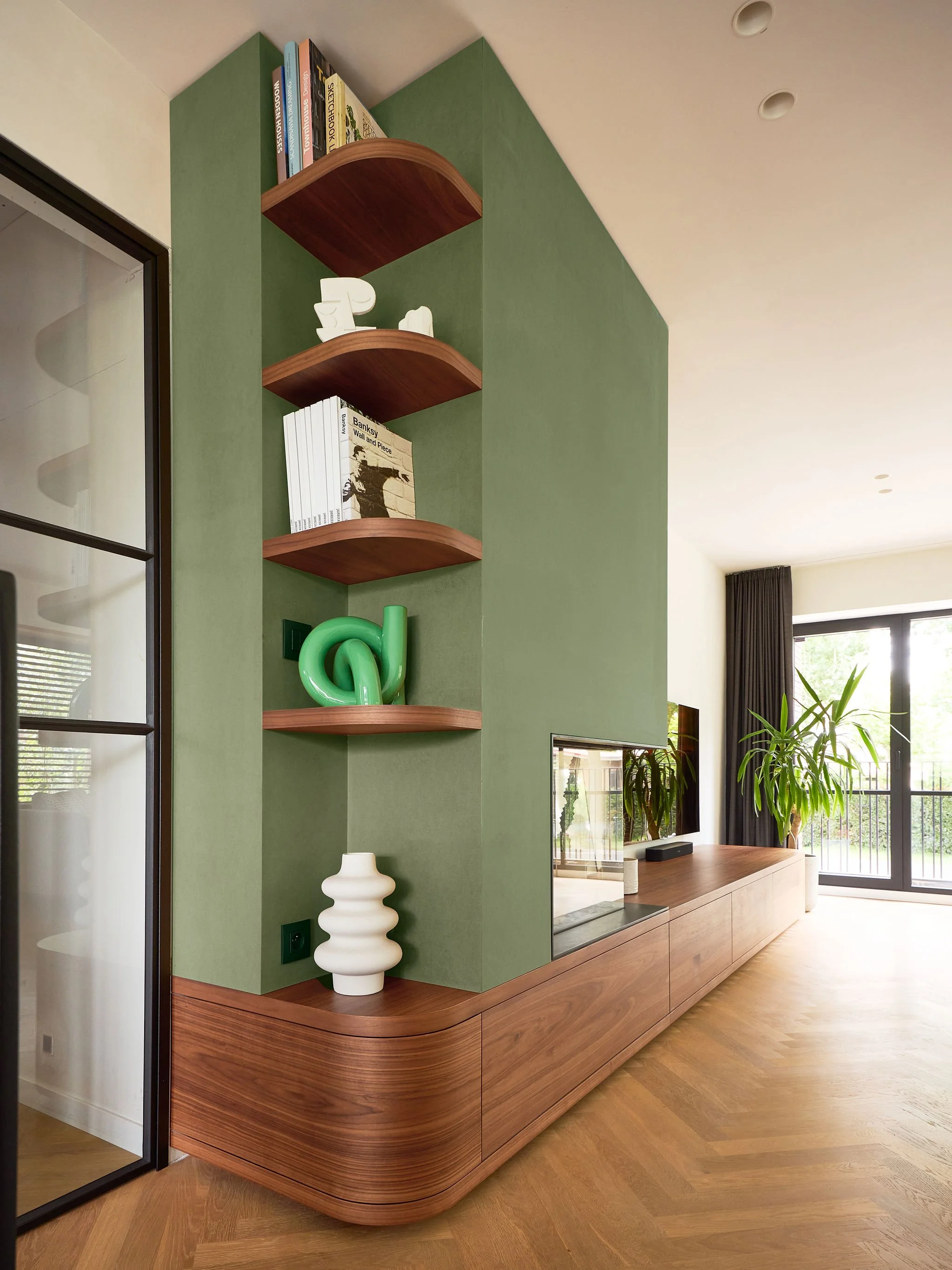 Haard- en tv-meubel in woning Sint-Kruis. Totaalontwerp woning met warme notelaar en afgeronde hoeken.
