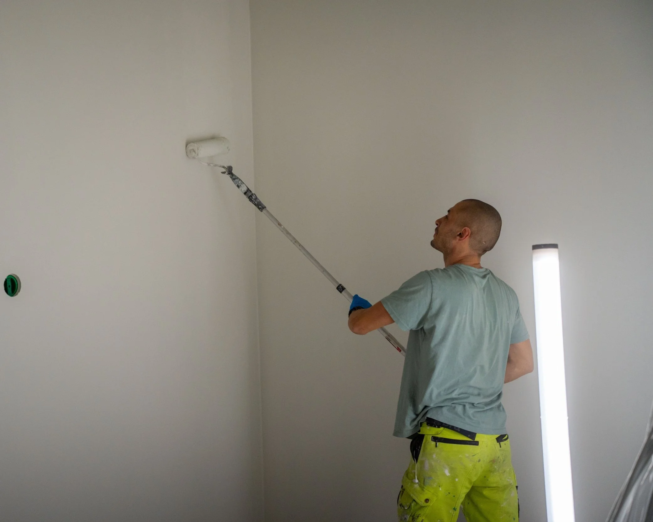 Fagarbeider som maler vegger, en av mange viktige oppdrag på et byggeprosjekt.