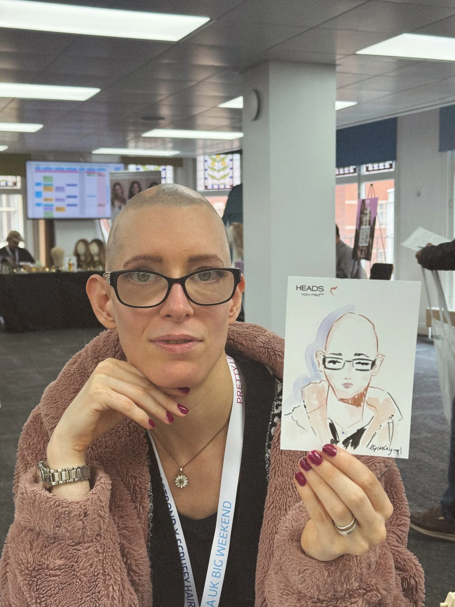 Woman with glasses and a short haircut holding a small watercolor portrait of herself by Eduard Illustrates