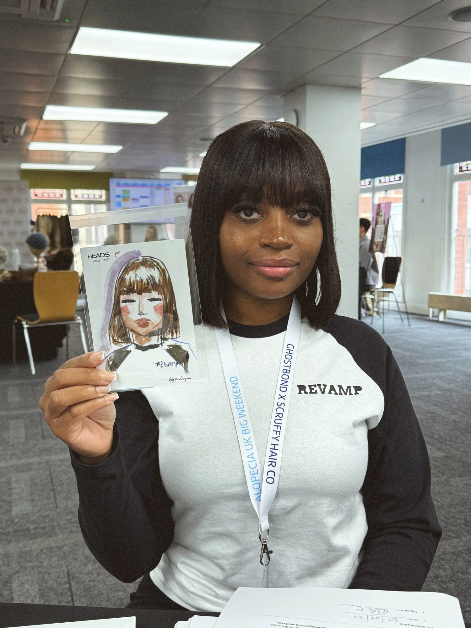 Woman with dark hair and bangs holding a hand-drawn illustration of herself by Eduard Illsutrates