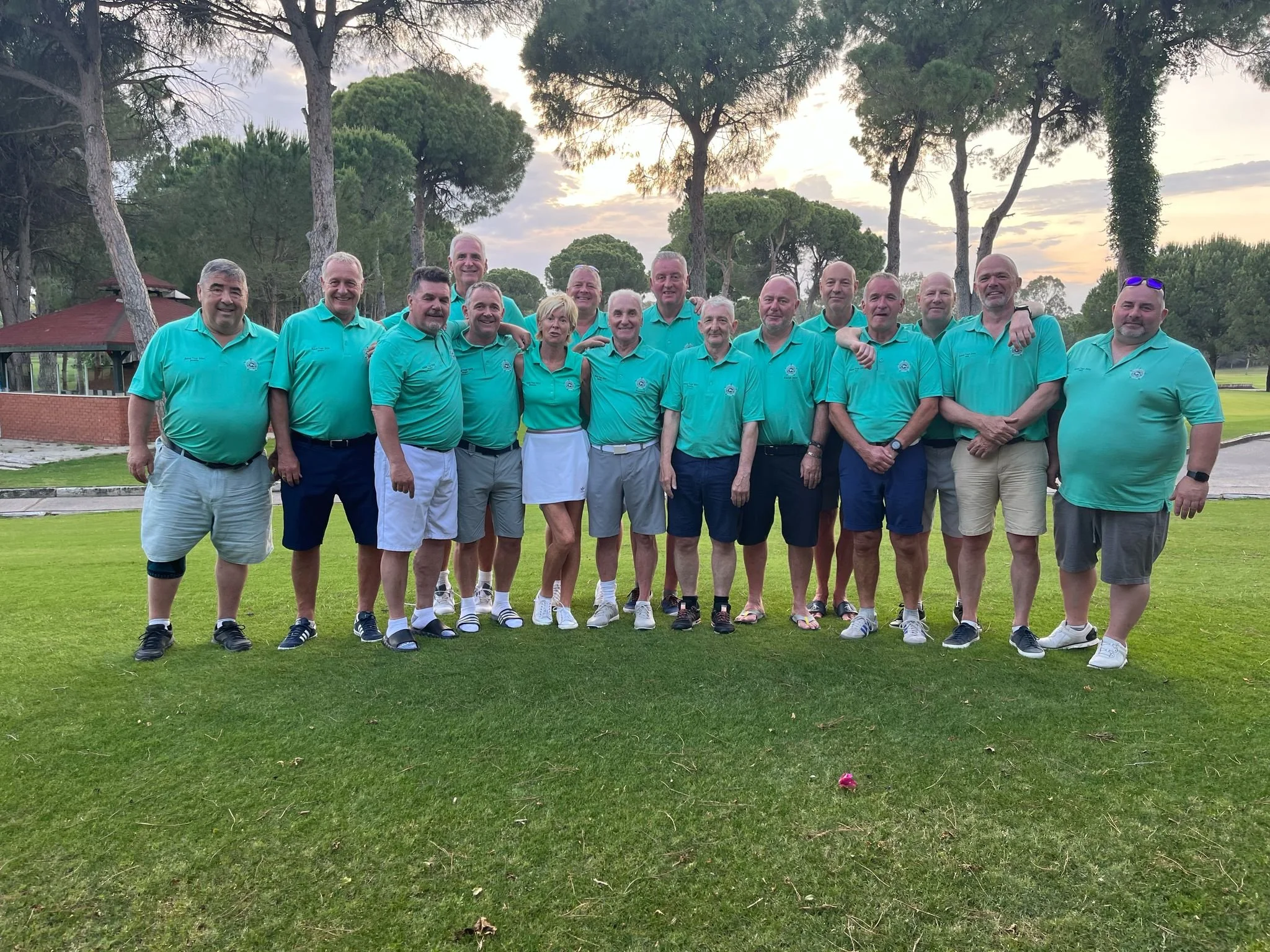 Group of people wearing matching teal shirts on a golf course
